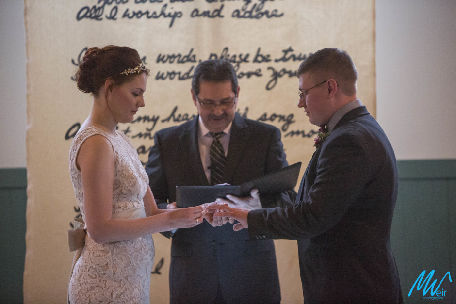 bride and groom exchanging rings at trolley barn wedding venue