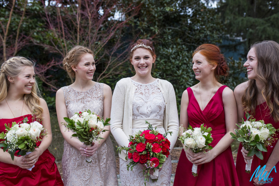 bridesmaids wearing red dresses and red rose bouquets