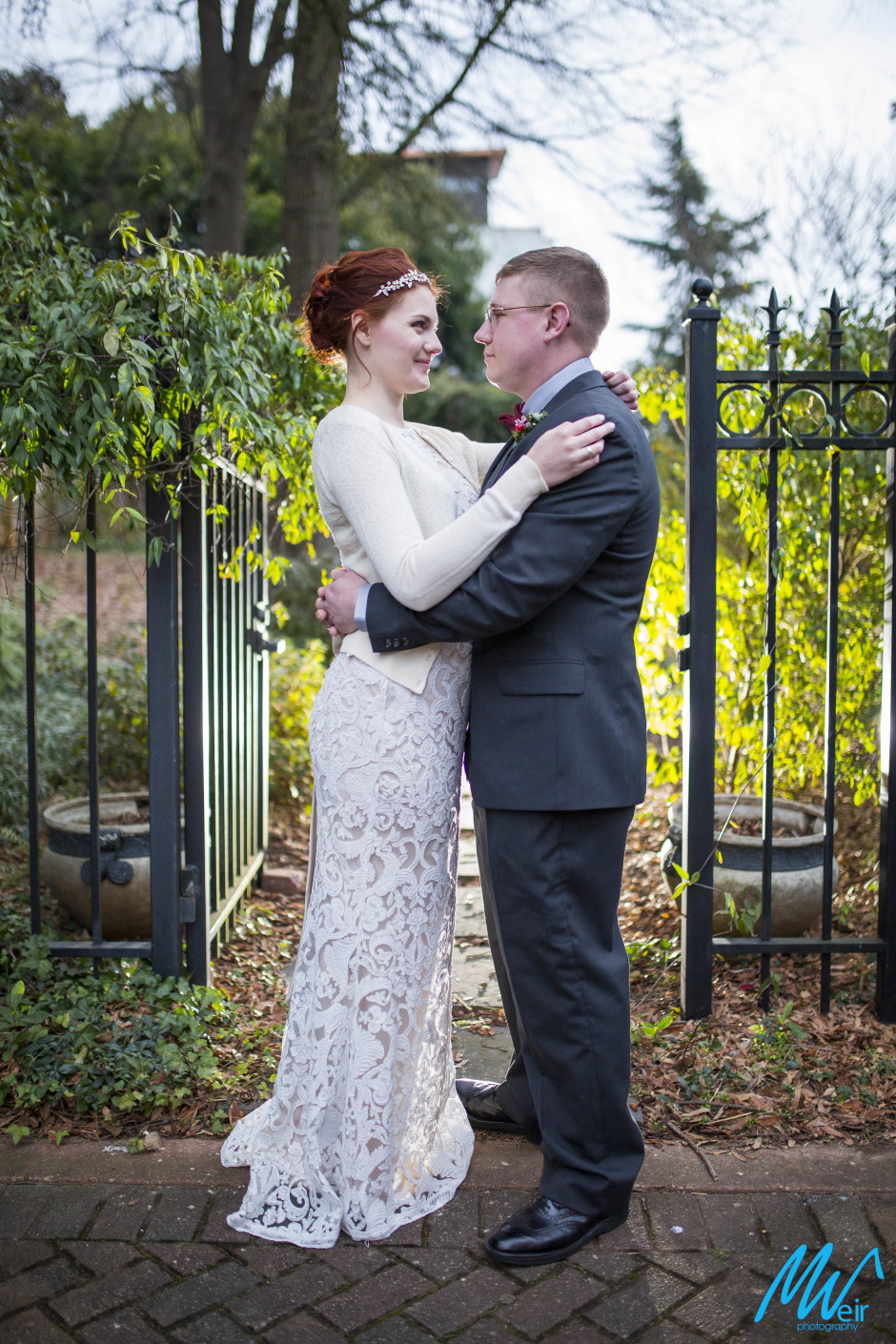 bride and groom sharing moment in front of wrought iron gate and vines