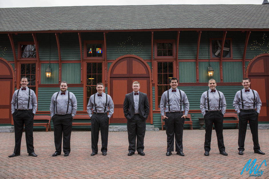 groomsmen wearing bowties and suspenders outside trolley barn