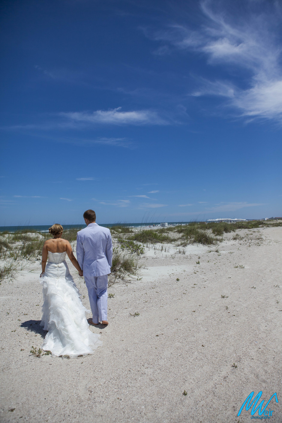 bride and groom walking on the beach holding hands