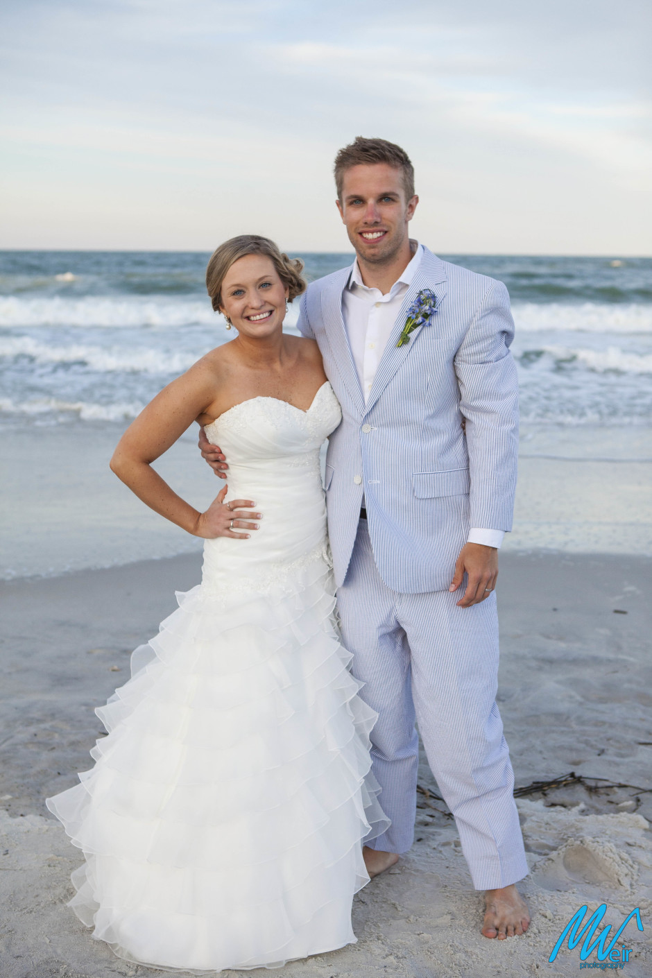 bride and groom standing in front of the ocean on the beach