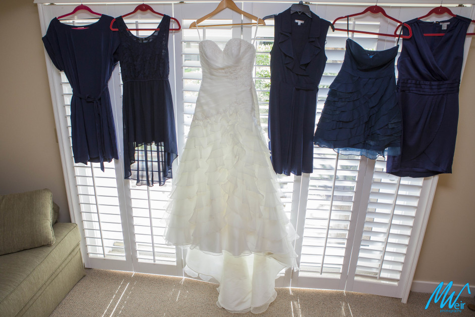bride and bridesmaid dresses hanging in front of a window