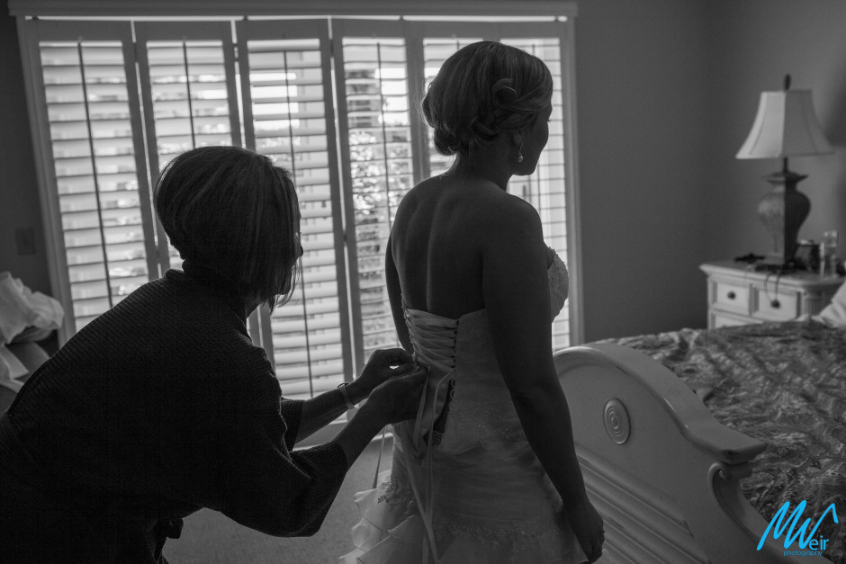 mother of the bride and bride getting laced up in her wedding dress