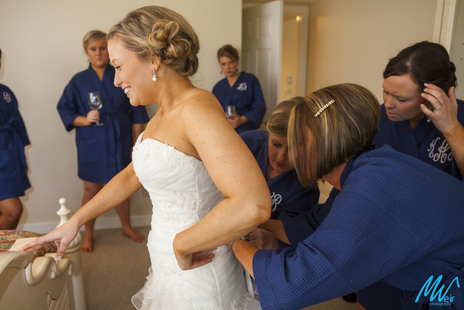 mother of the bride lacing daughters dress up on her wedding day