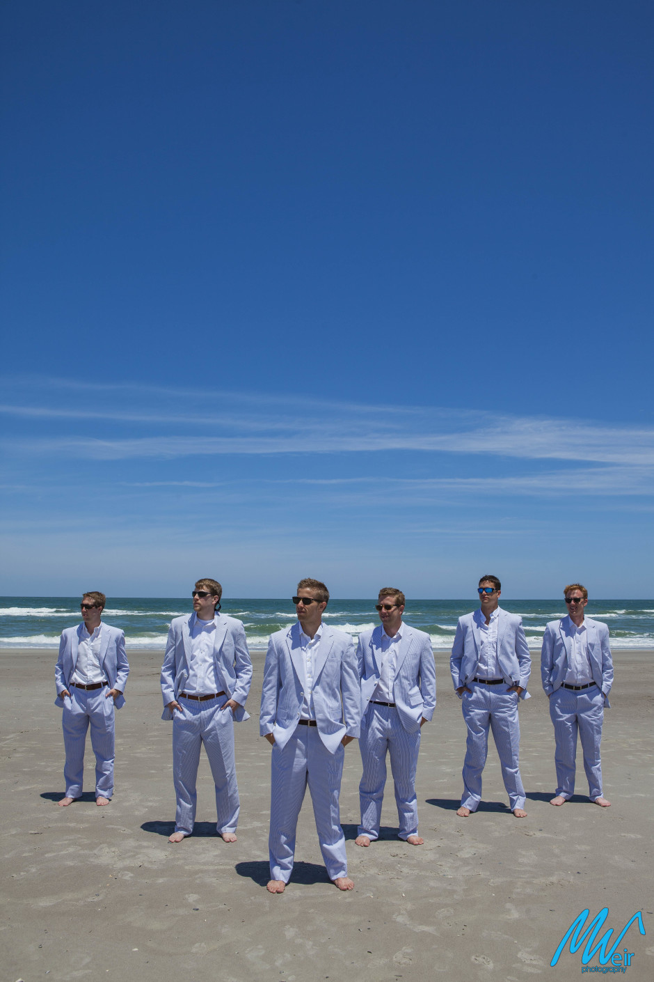 groomsmen wearing sun glasses on the beach in seersucker suits