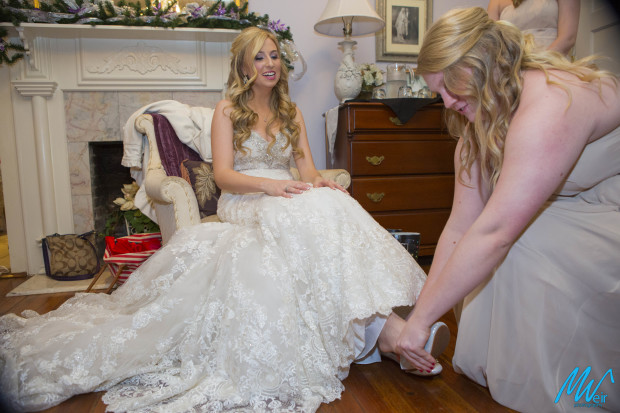 bridesmaid putting brides shoes on for her
