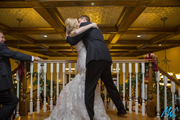 bride and groom kiss at top of the stair during grand entrance