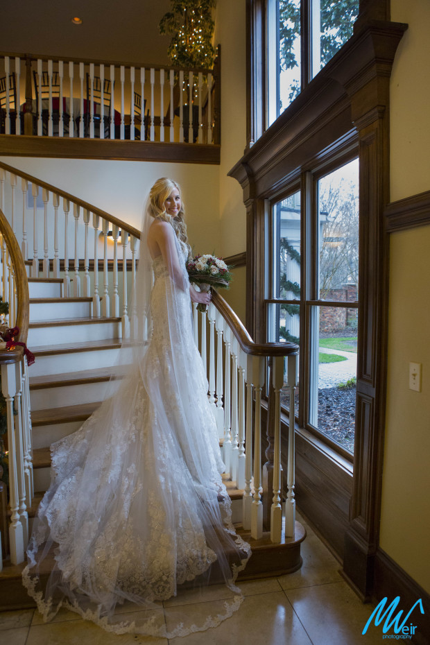 bride standing on grand staircase in front of huge window