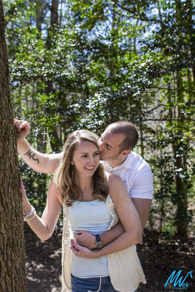 grooms kissing brides cheek by a tree