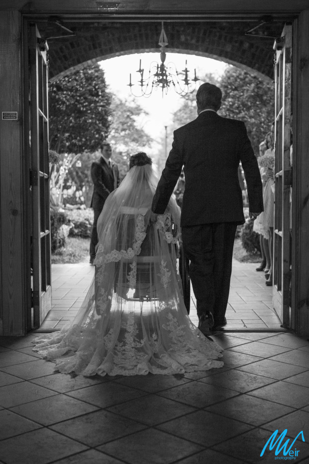 bride in a wheelchair being escorted by her father down aisle to wedding