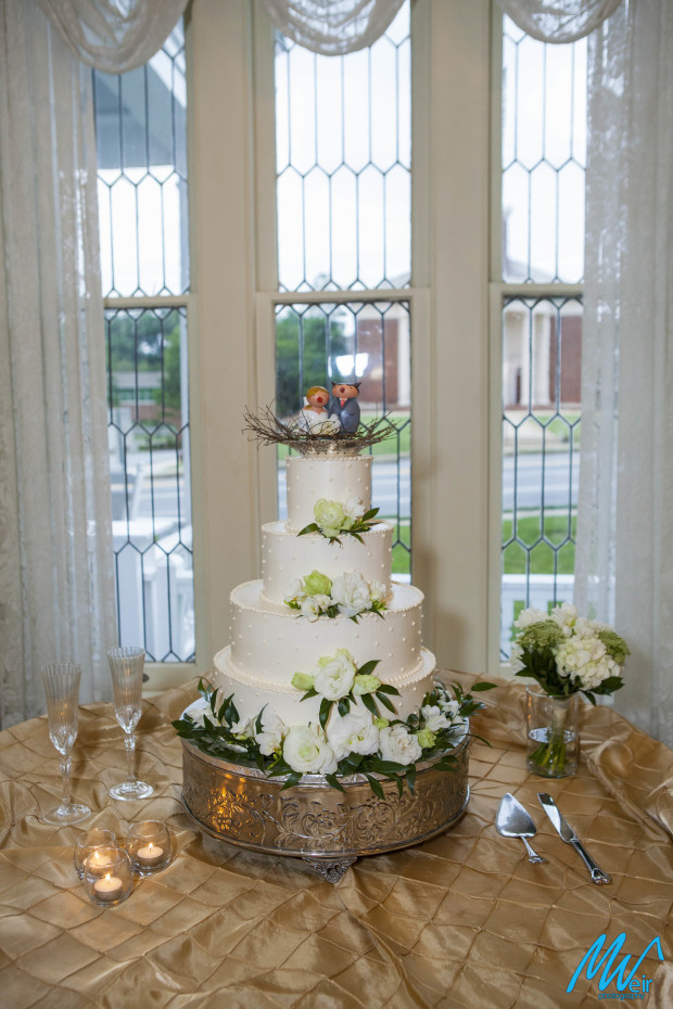 white four tiered wedding cake with wooden birds as cake toppers