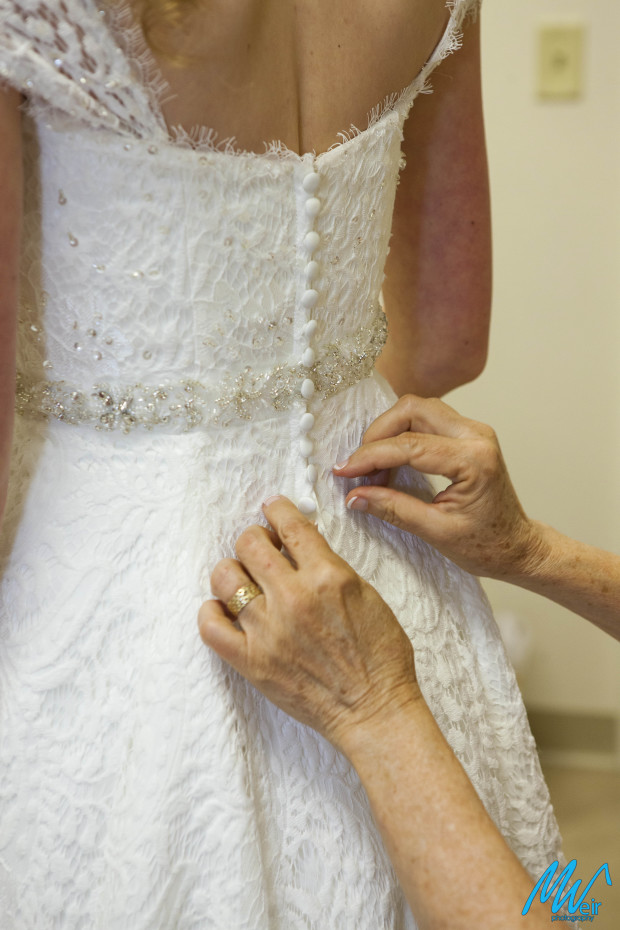 mother of the bride buttoning her daughter in her wedding dress