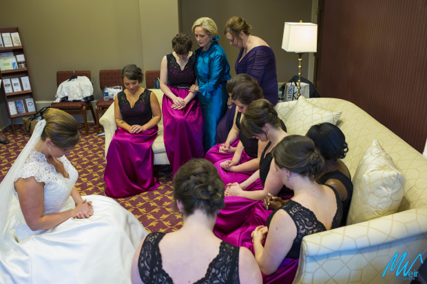 bridesmaids and bride pray before the ceremony