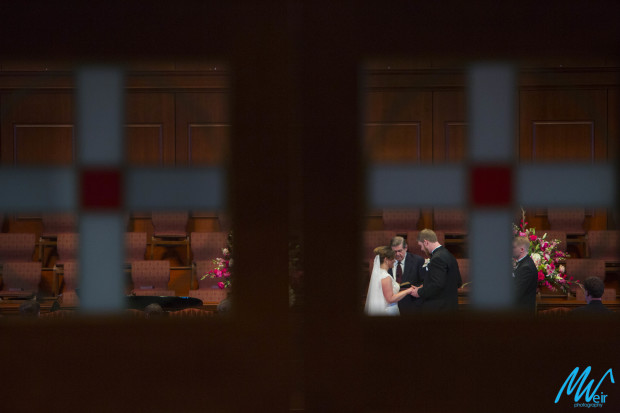 bride and groom exchange rings through church windows