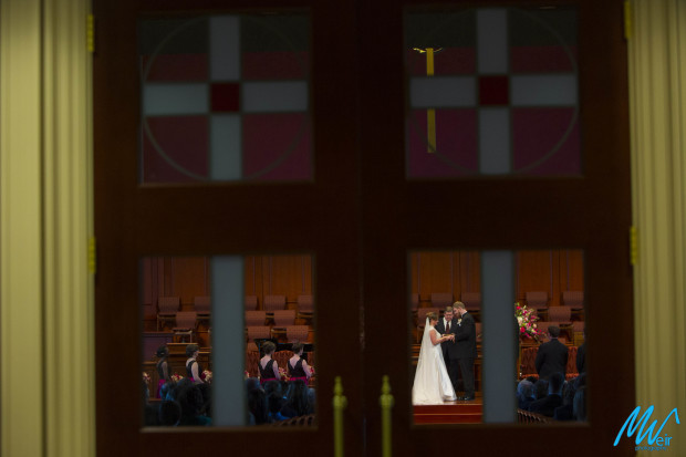 bride and groom pray through the church windows