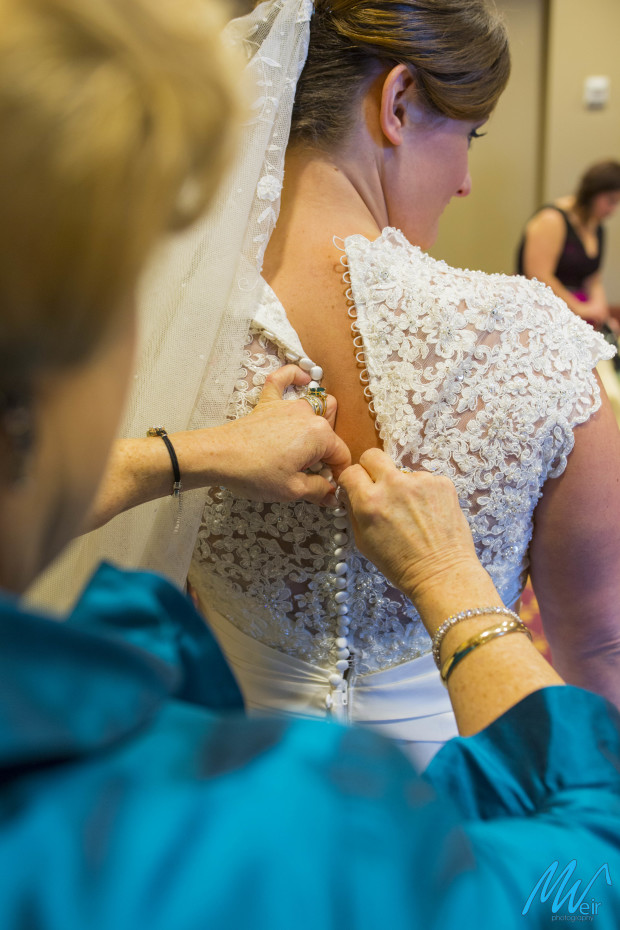 mother buttons up brides dress