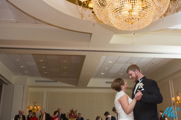 bride and groom dancing under chandelier
