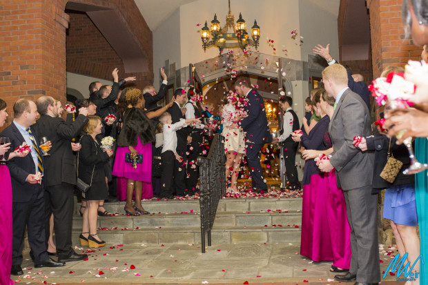 bride and groom kiss with flower petals thrown at them