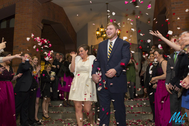 couple leaves reception with rose petals thrown at them