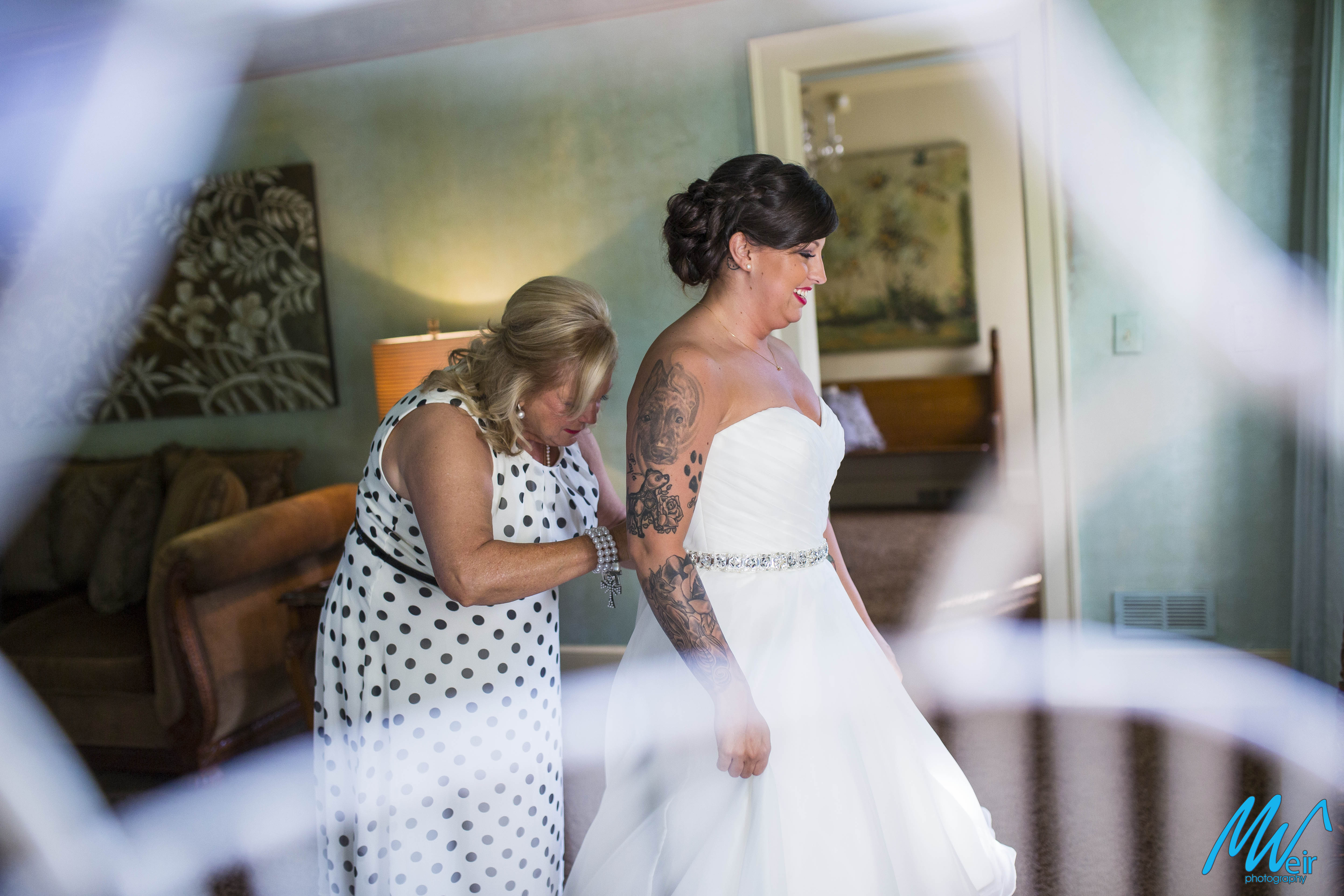 mother of bride helping bride into dress