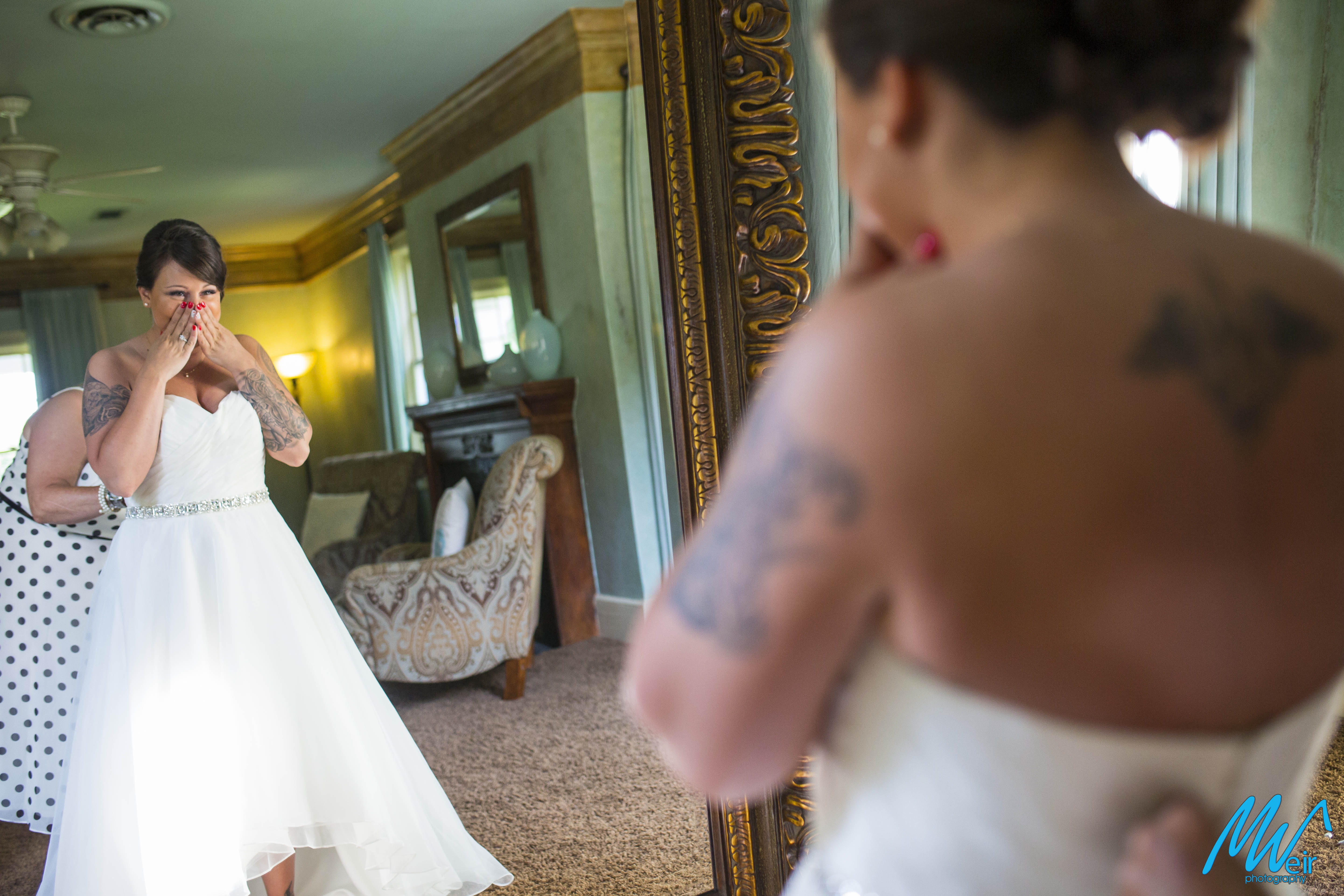 bride getting emotional while putting on dress