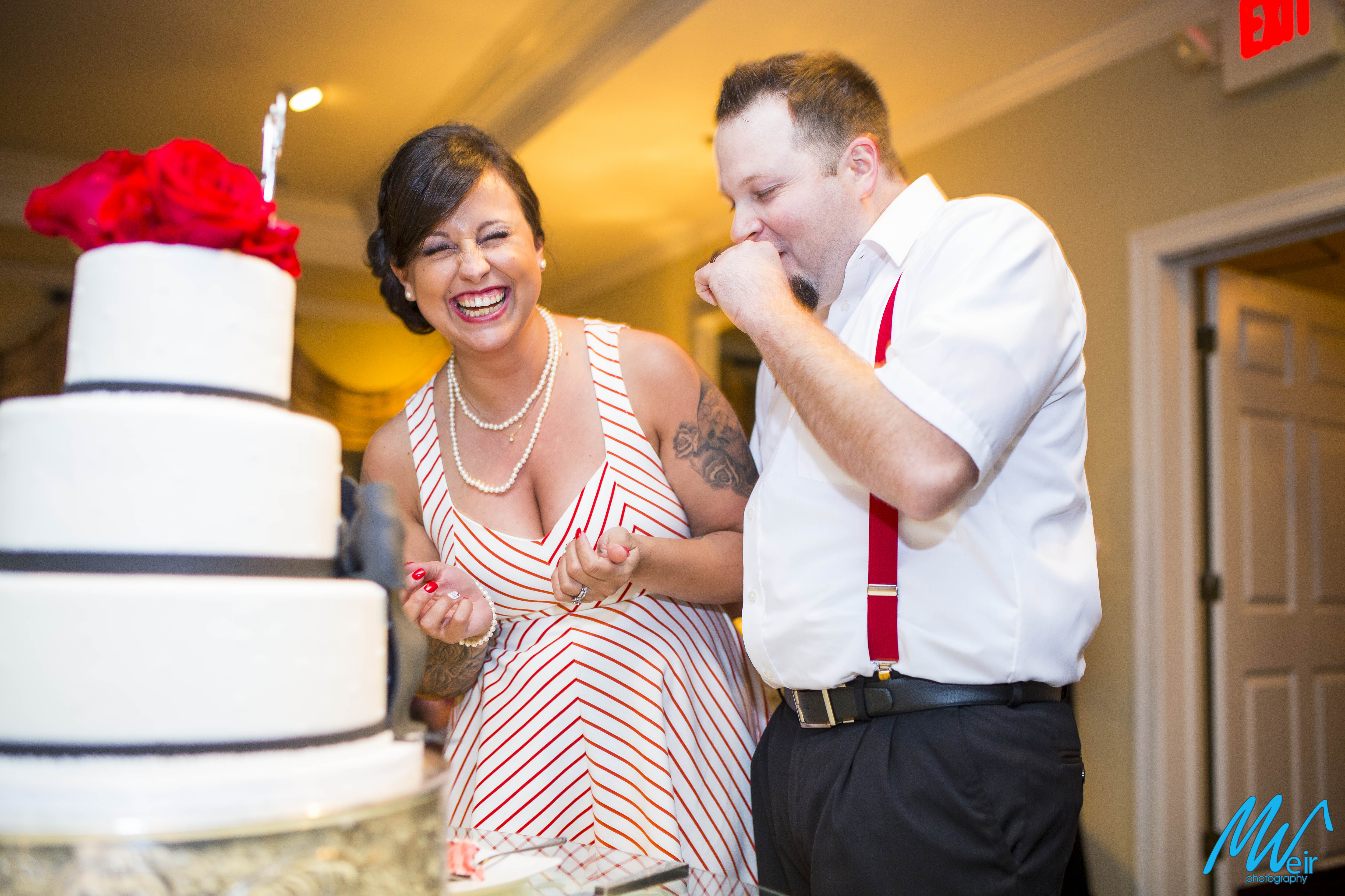 bride laughs after shoving cake into grooms mouth