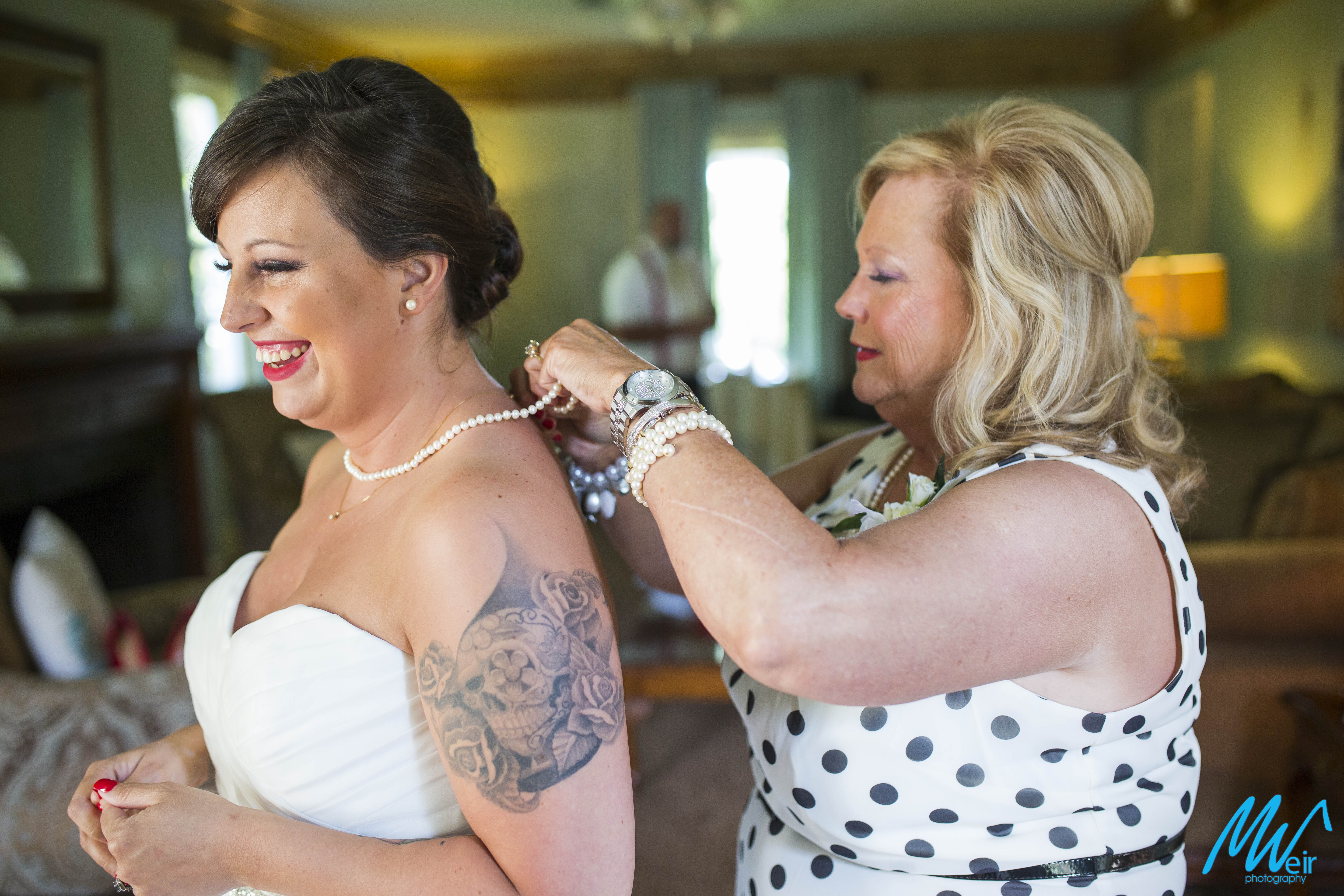 mother of the bride putting pearl necklace on bride
