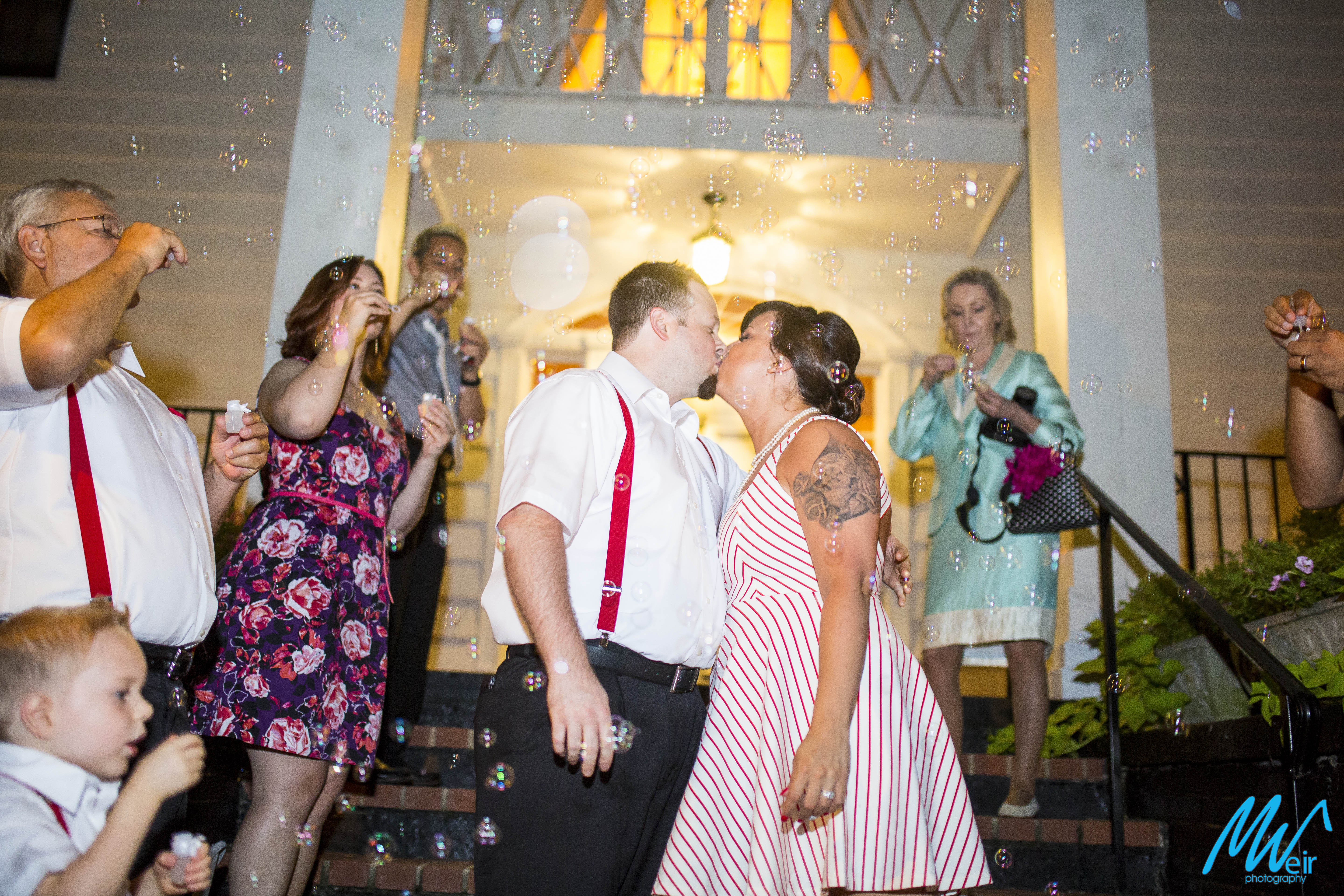 bride and groom kiss among bubbles