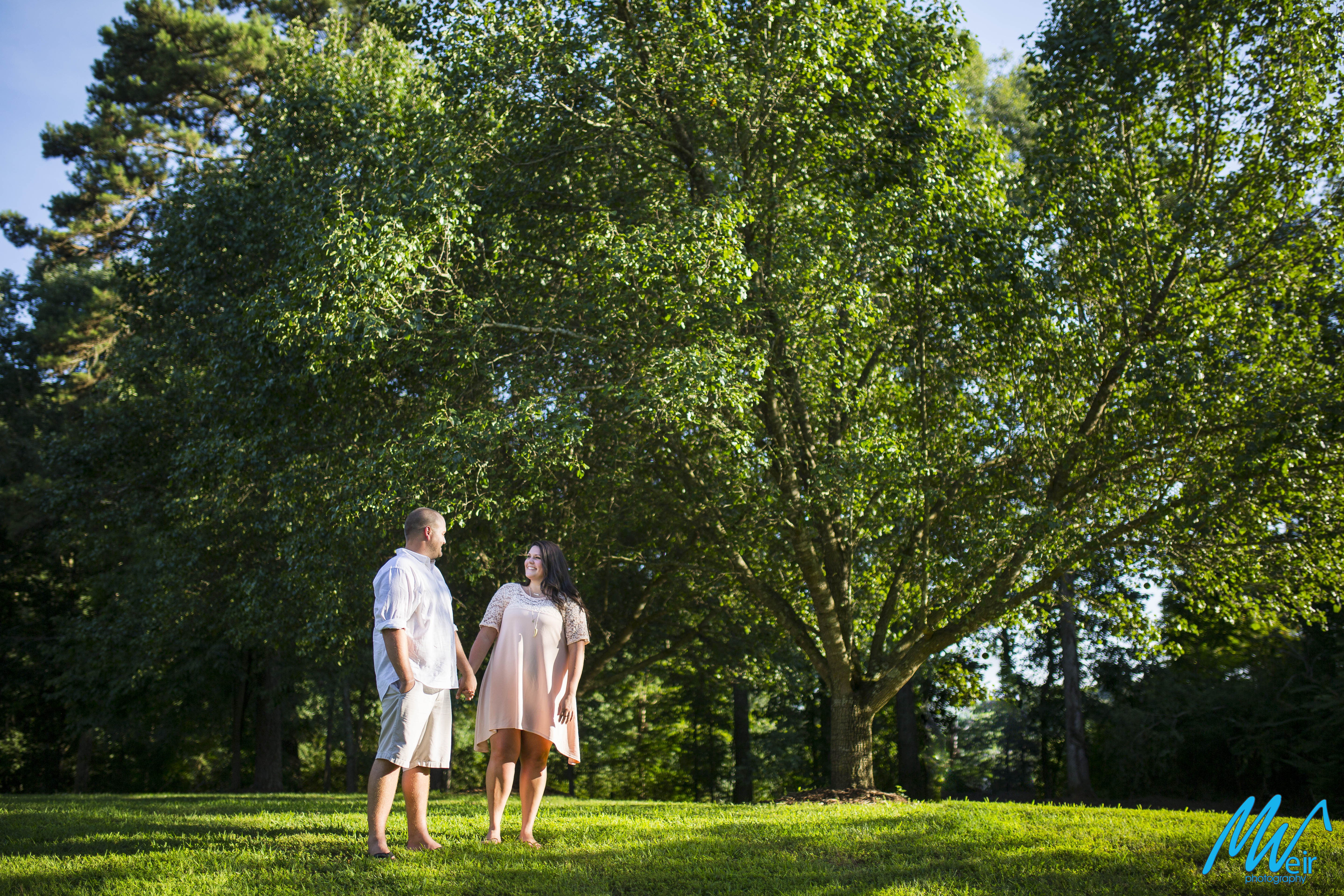 bride and groom stand barefoot in a field under trees