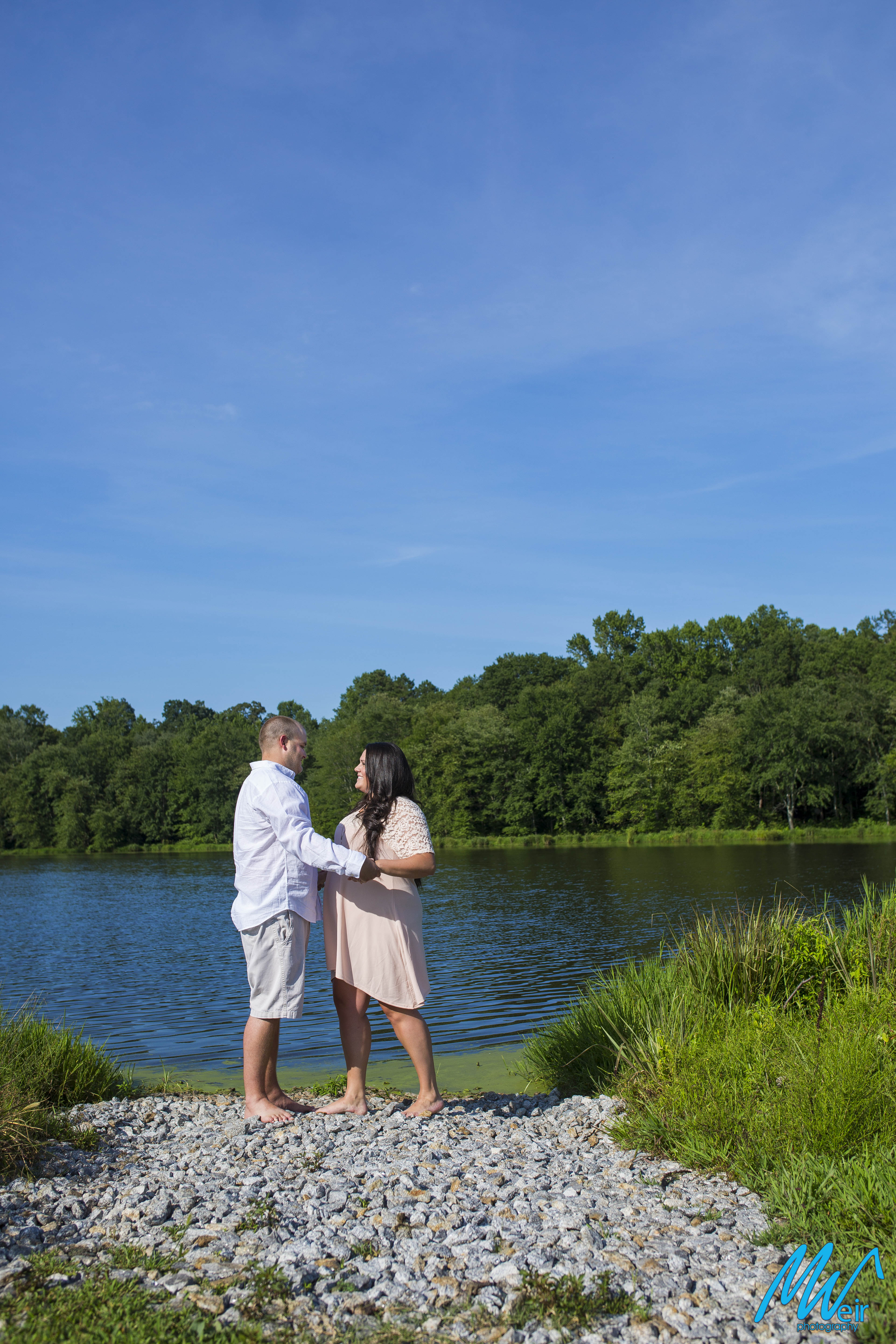 bride and groom standing in front of a lake
