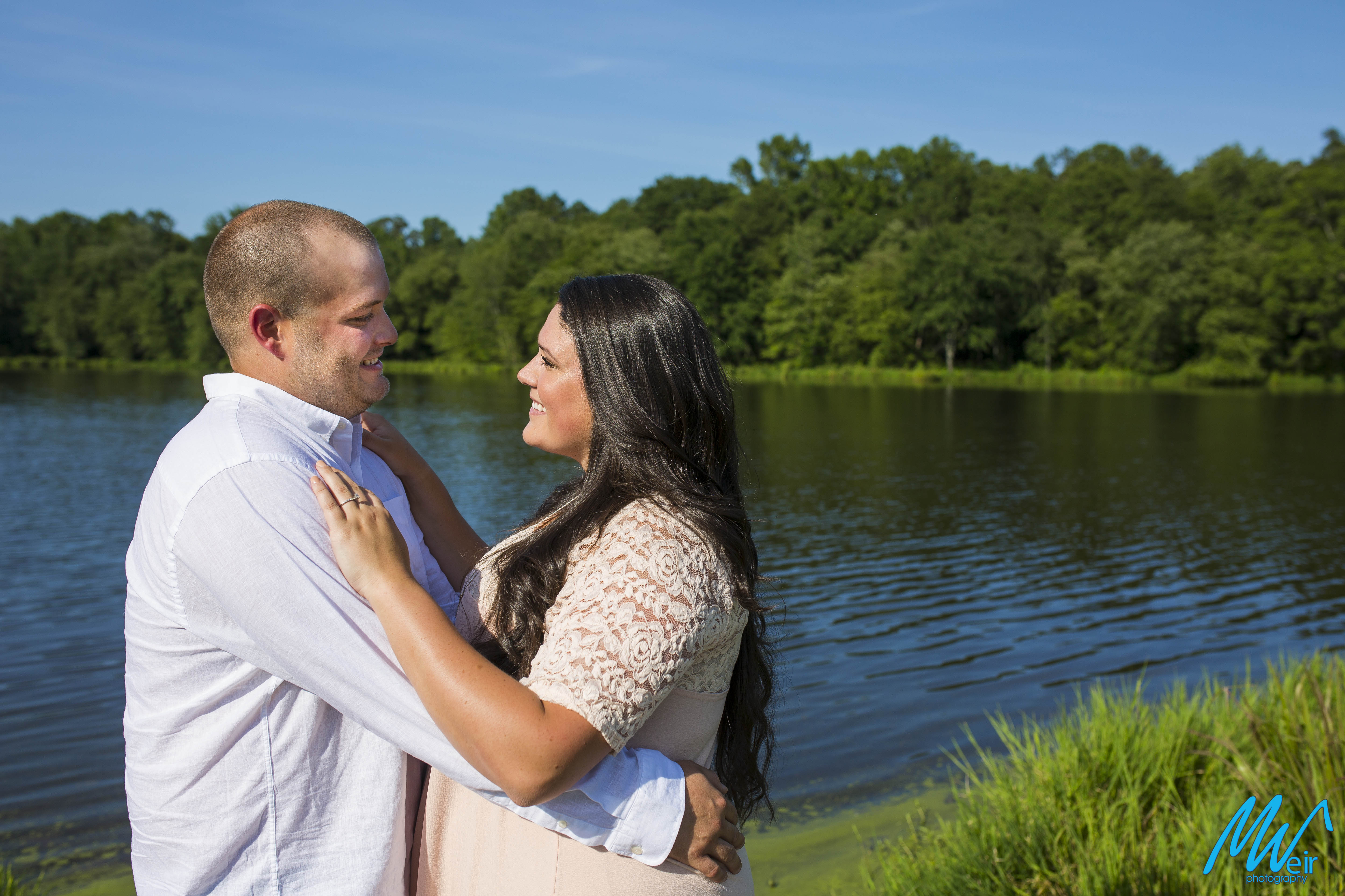 bride and groom smiling in front of lake