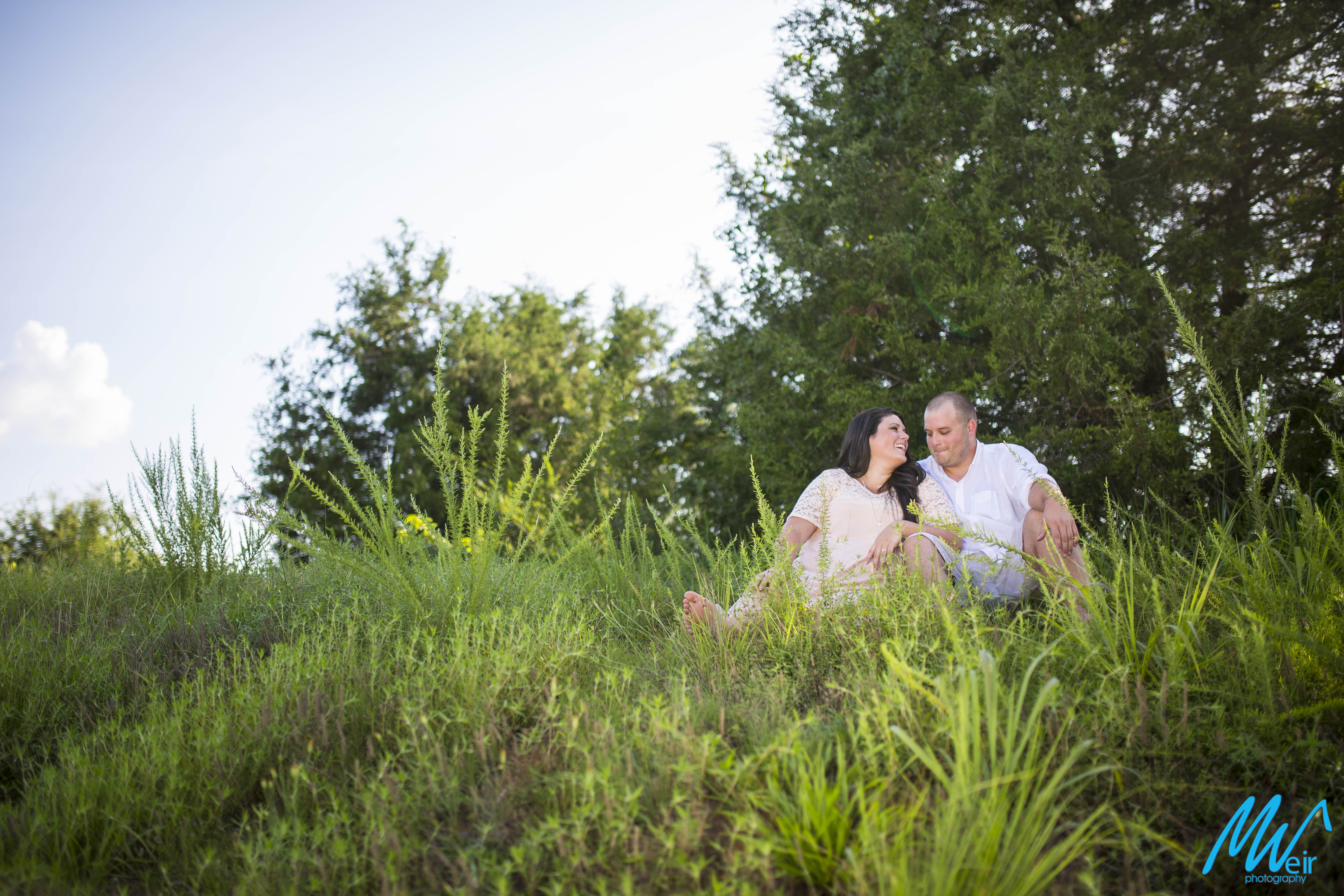 bride and groom sitting in a field