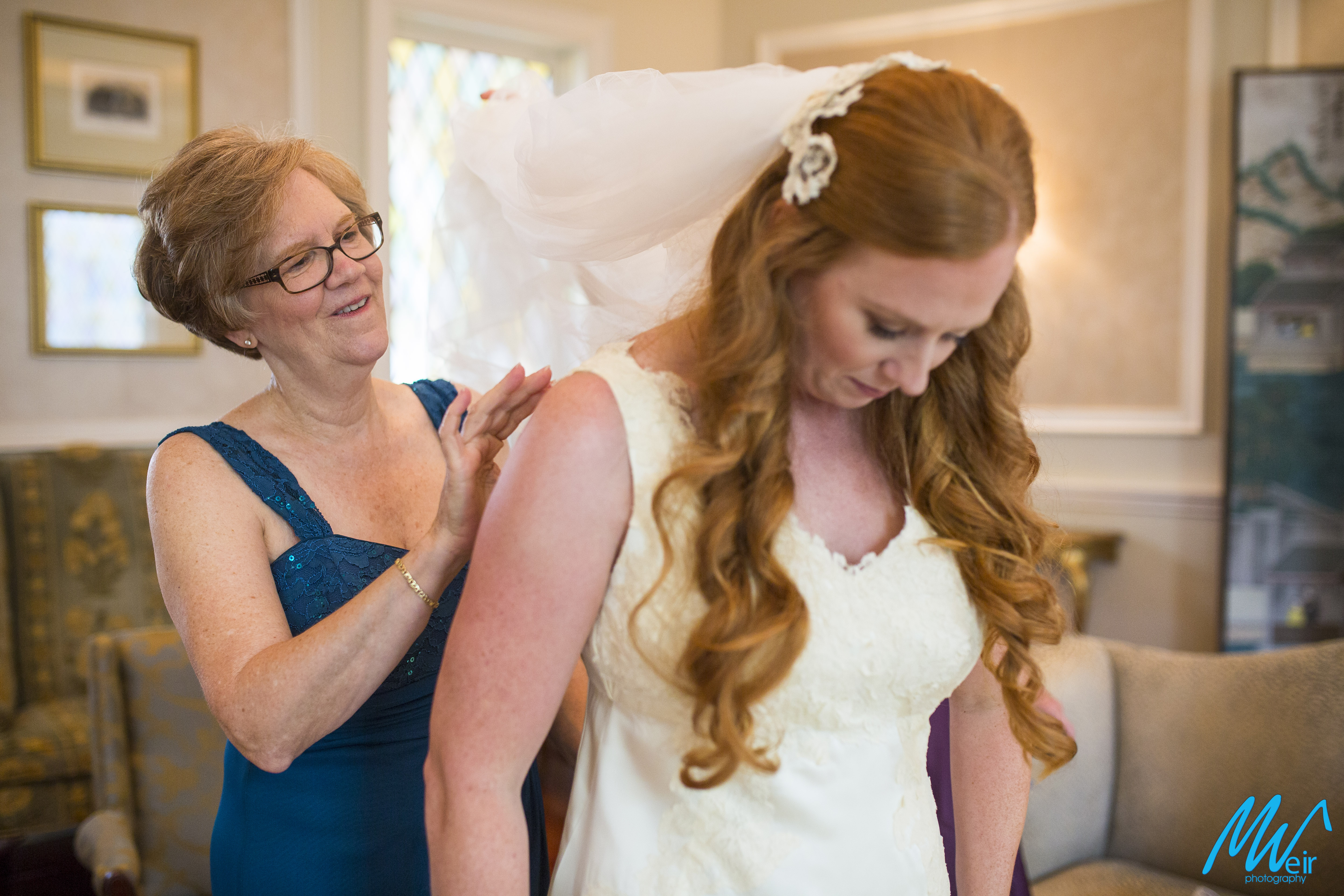 mother of the bride helping her daughter into her dress