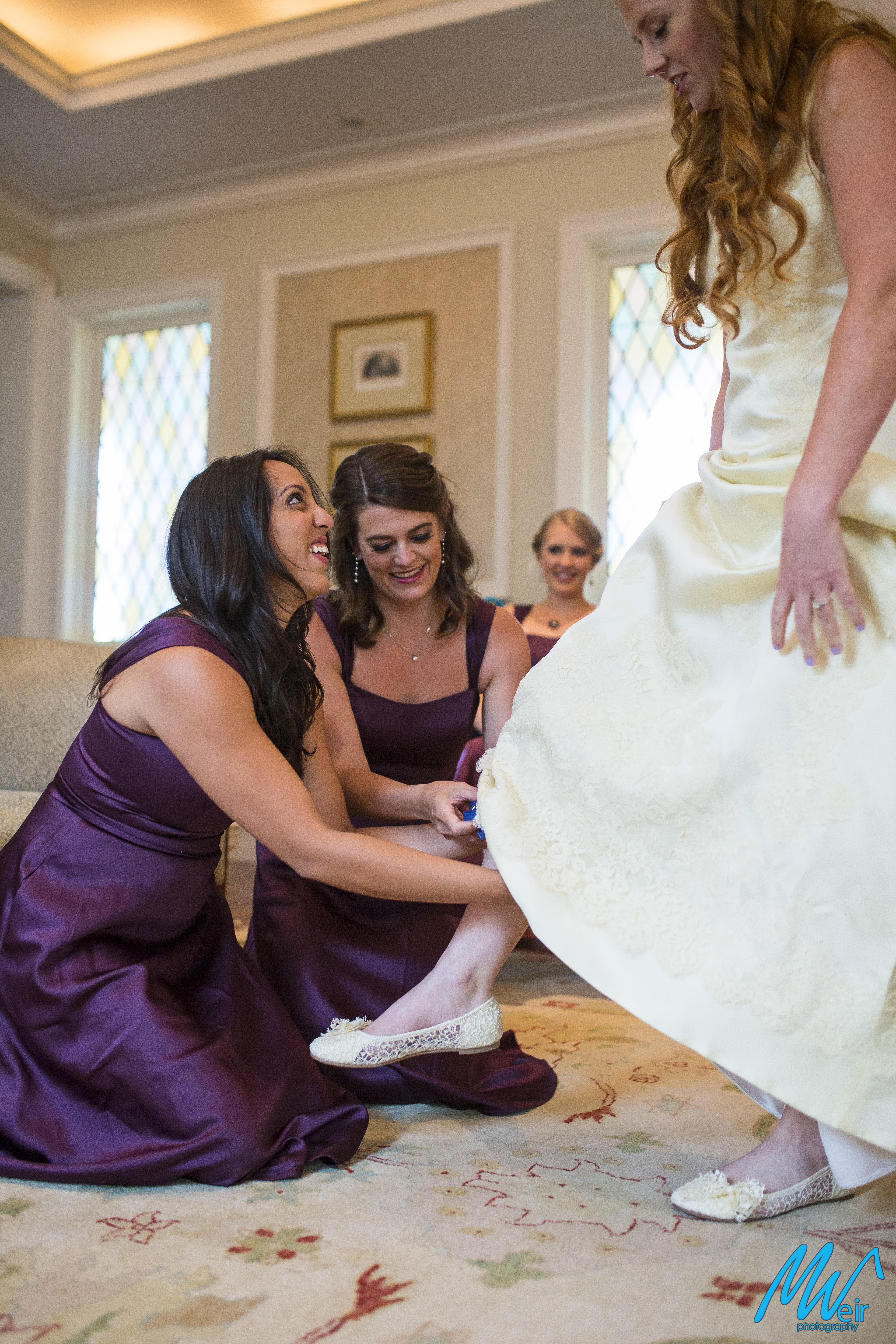 bridesmaids help put garter on bride