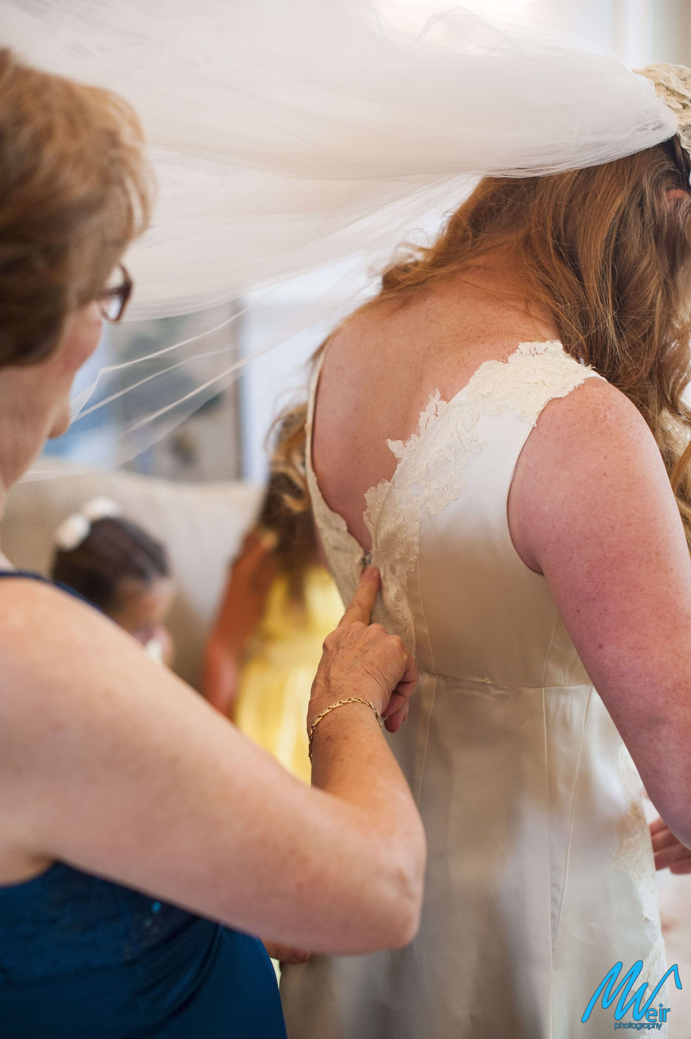 mother of the bride helps zip up brides dress
