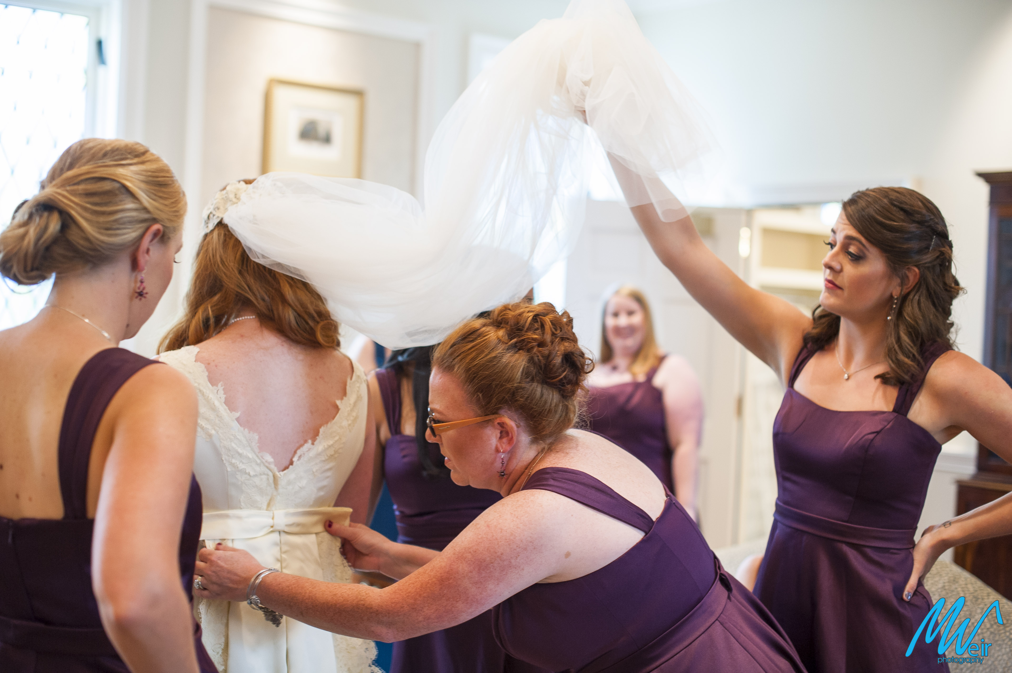 brides sister helps put detachable train on the brides dress