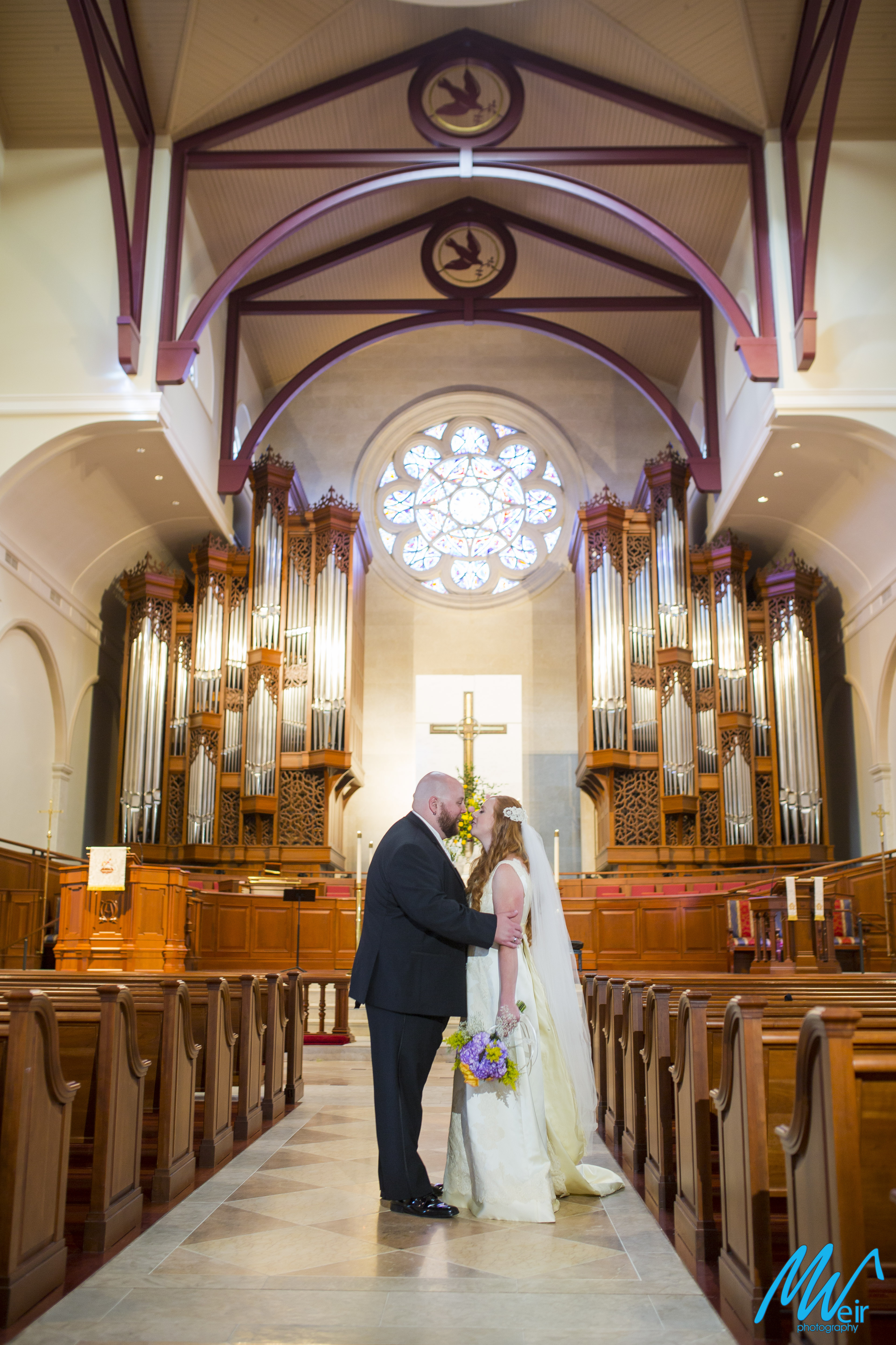 bride and groom stand in the aisle of church sanctuary