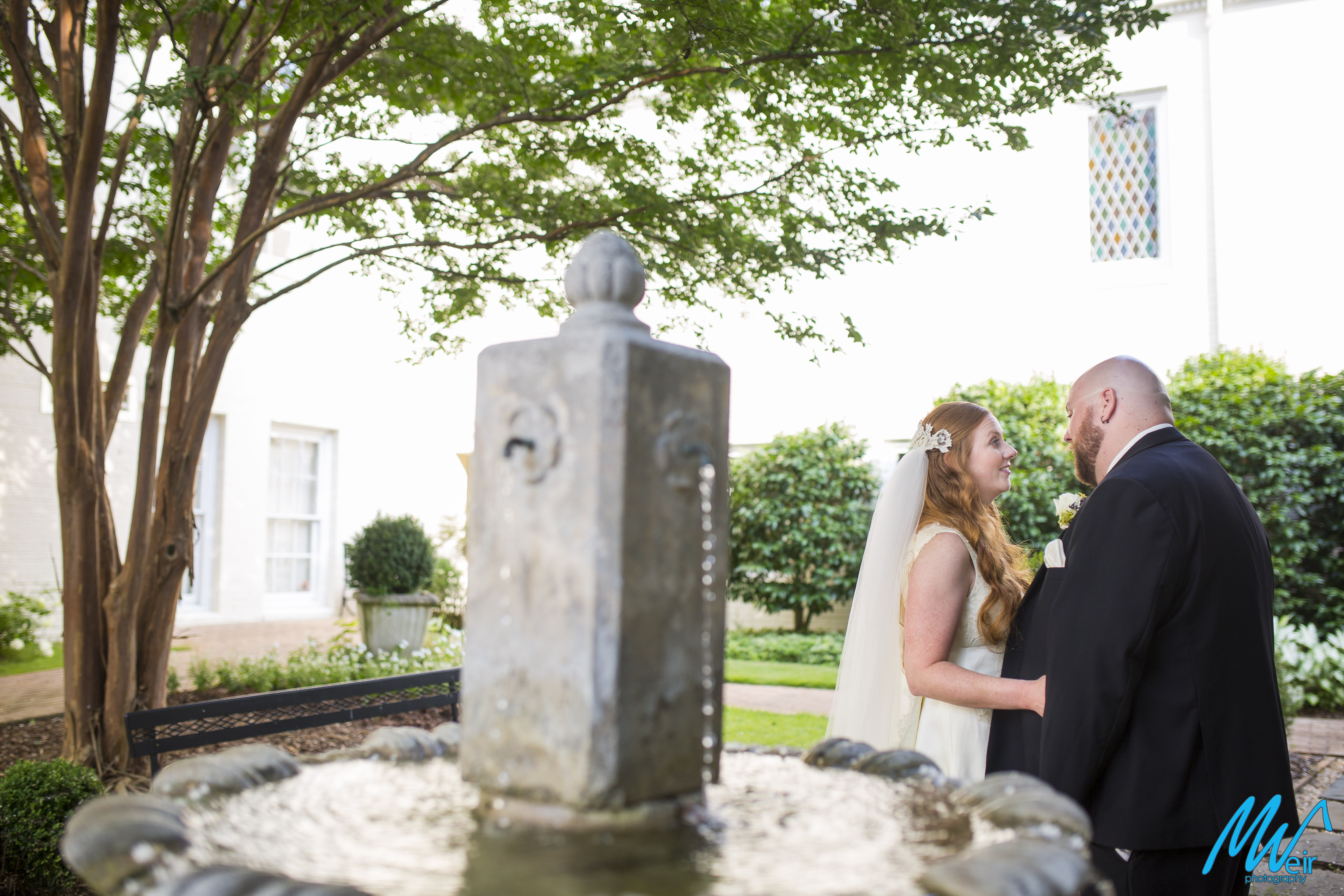 bride and groom standing behind a fountain