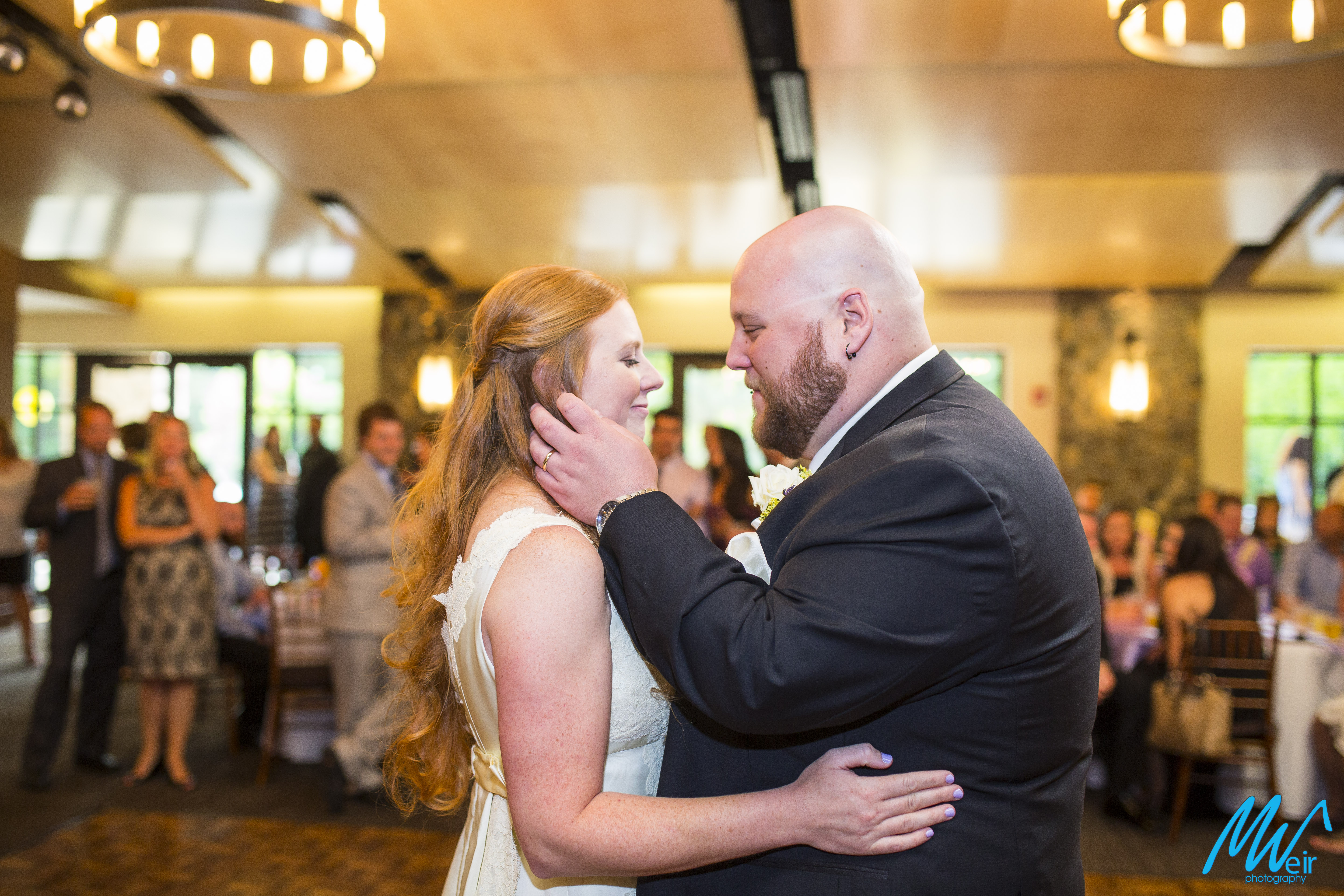 groom brushes brides hair out of her face after first dance