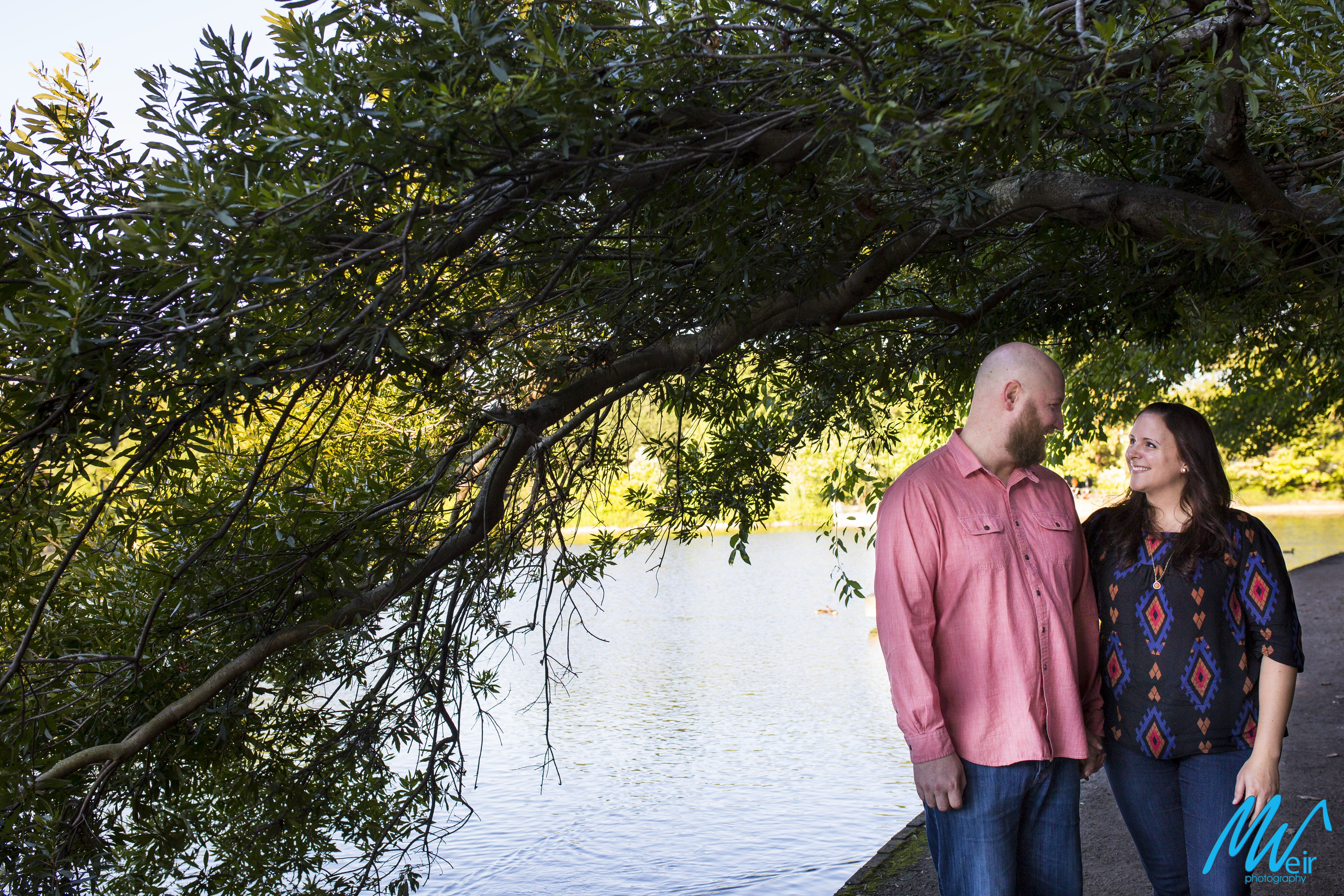 bride and groom gaze at each other under a low sweeping tree by a lake