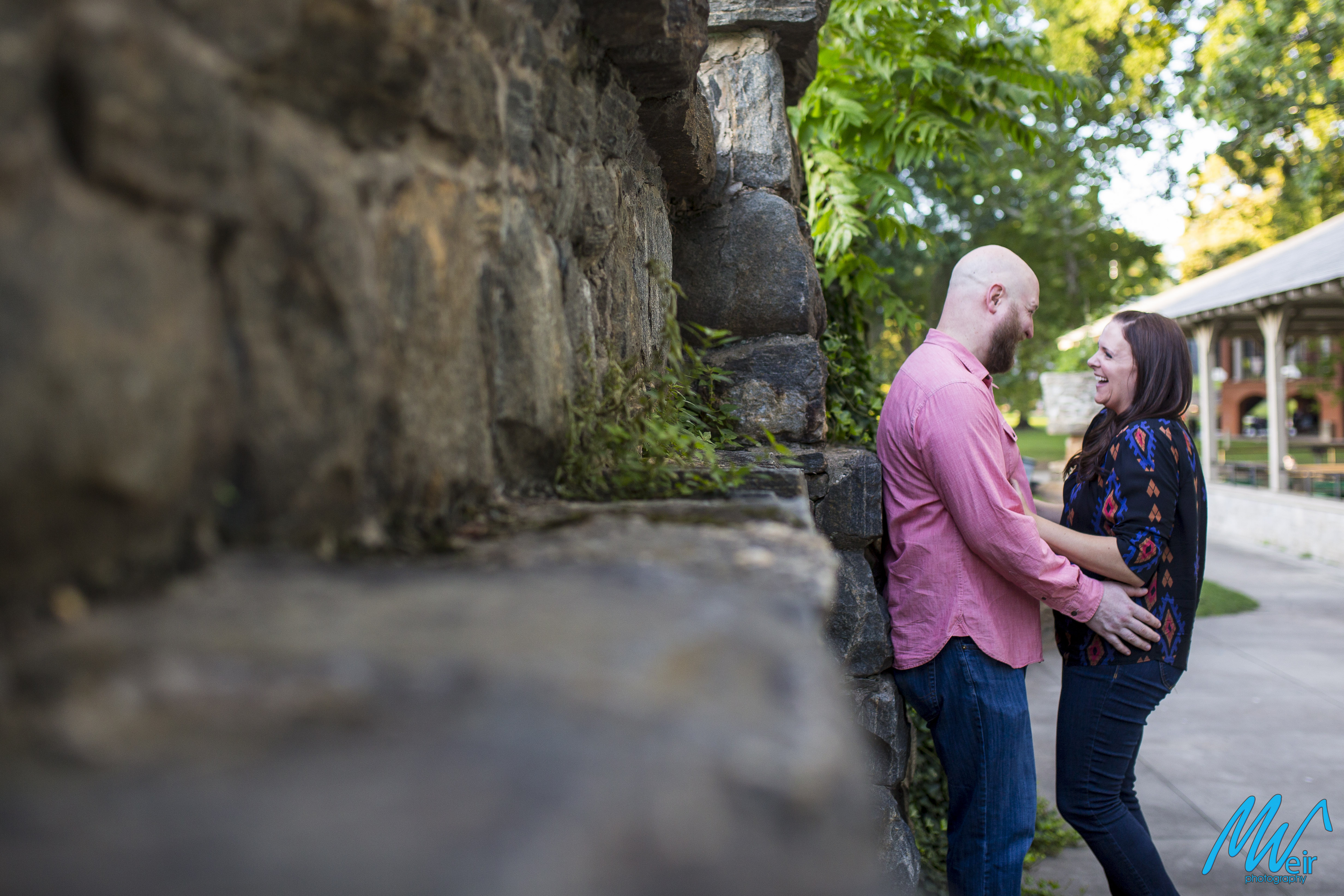 bride tickles groom in front of stone wall