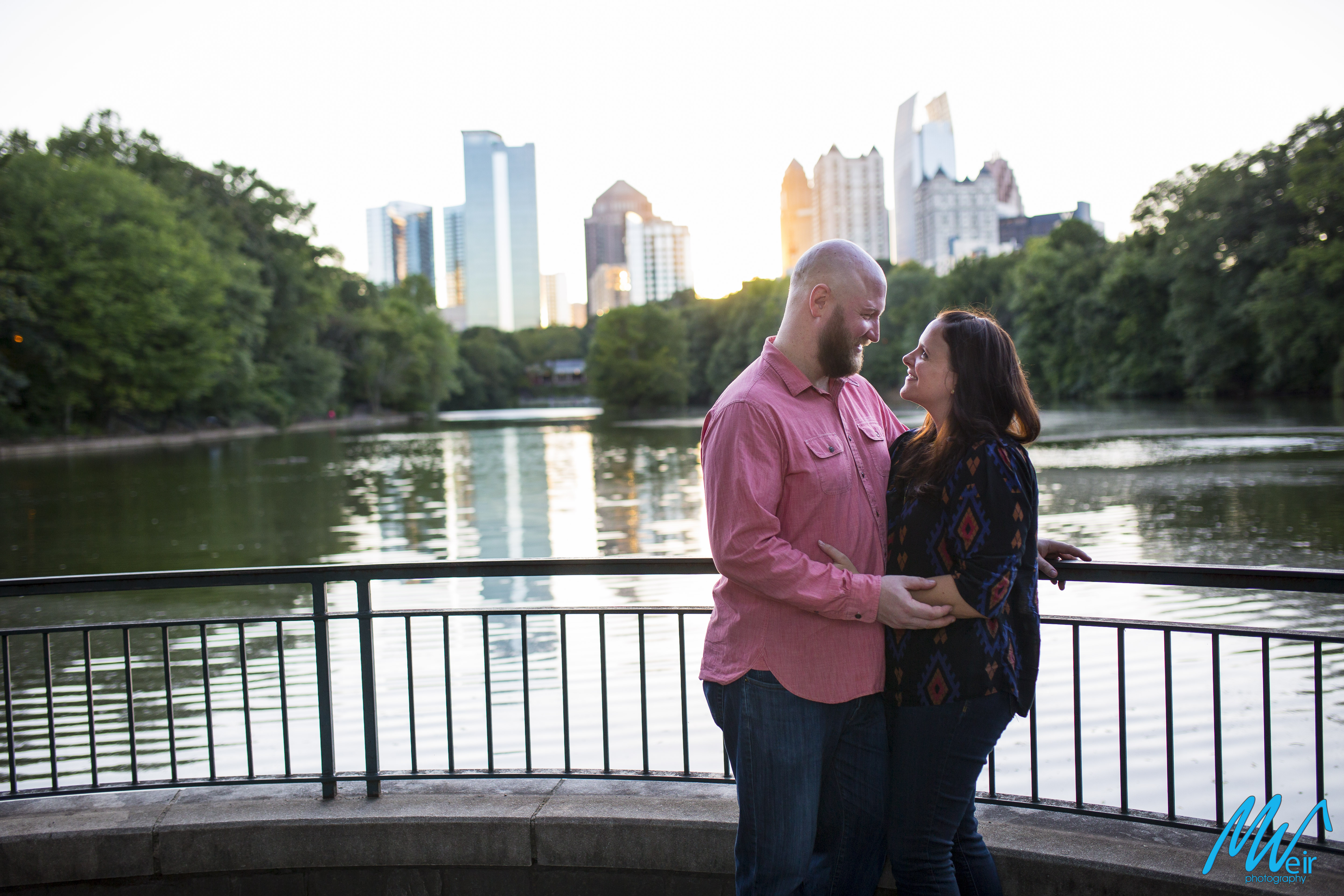 bride and groom look at each other in front of piedmont park lake and atlanta skyline