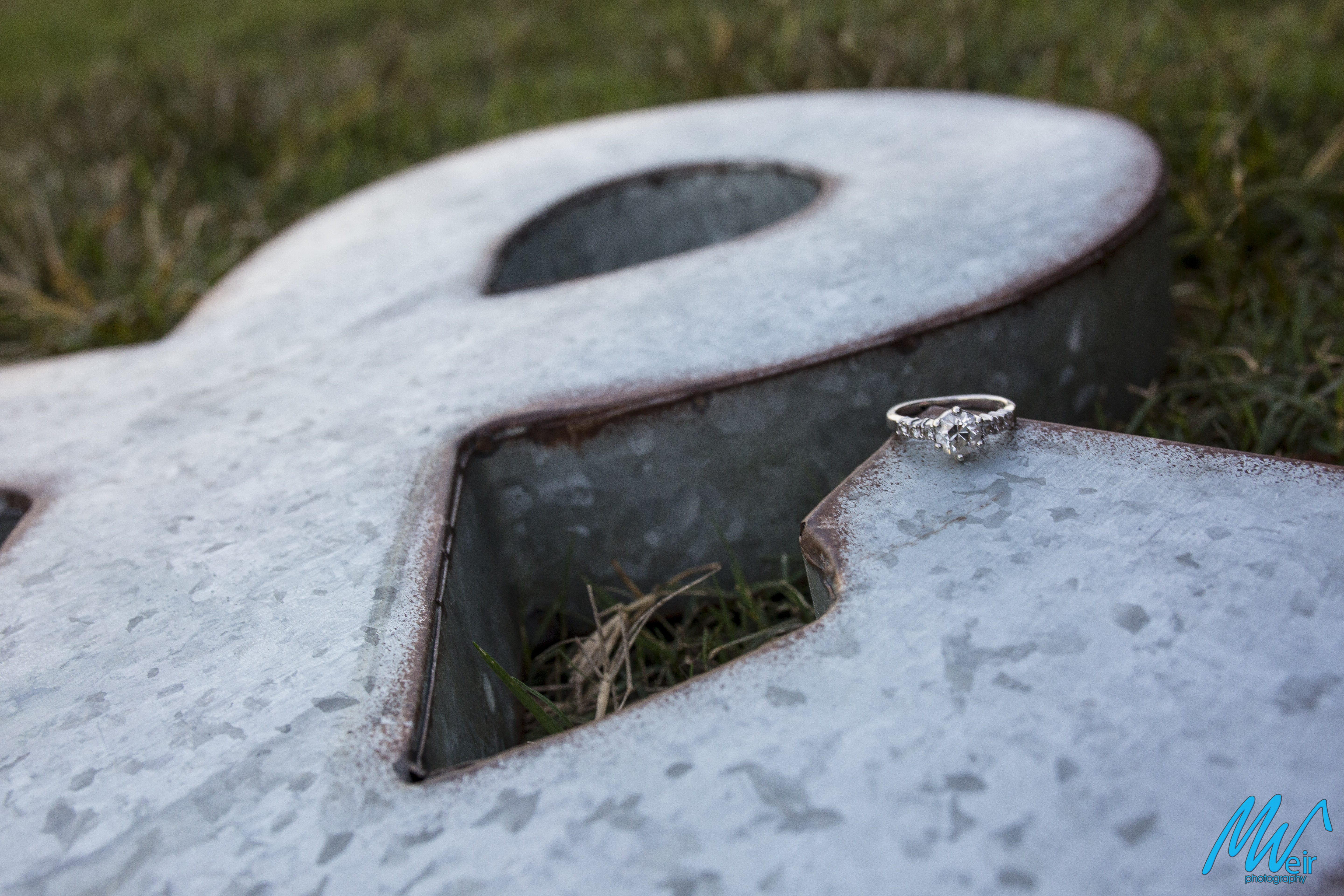 detail of diamond engagement ring on a metal and sign