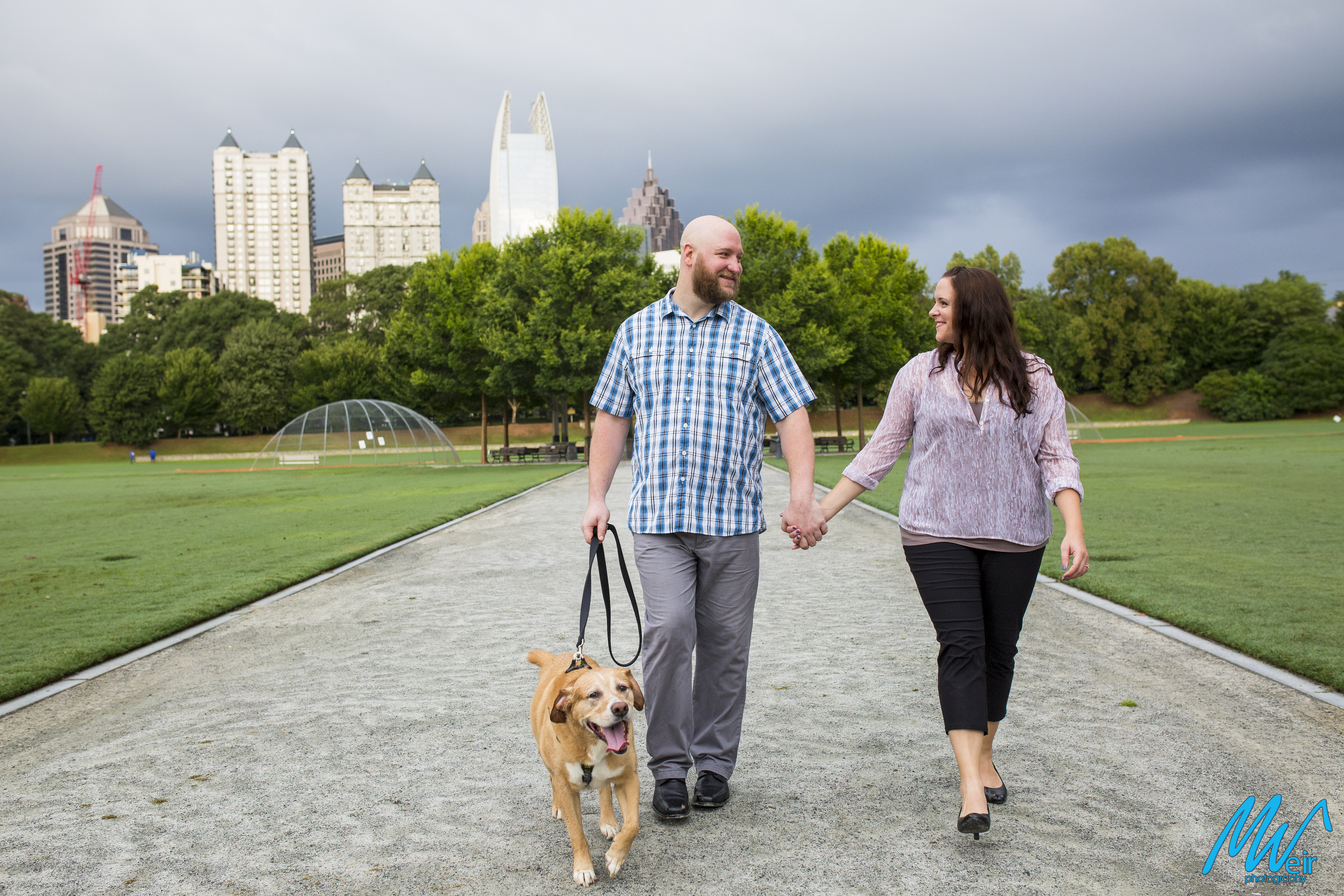 couple walking through piedmont park holding hands walking their dog