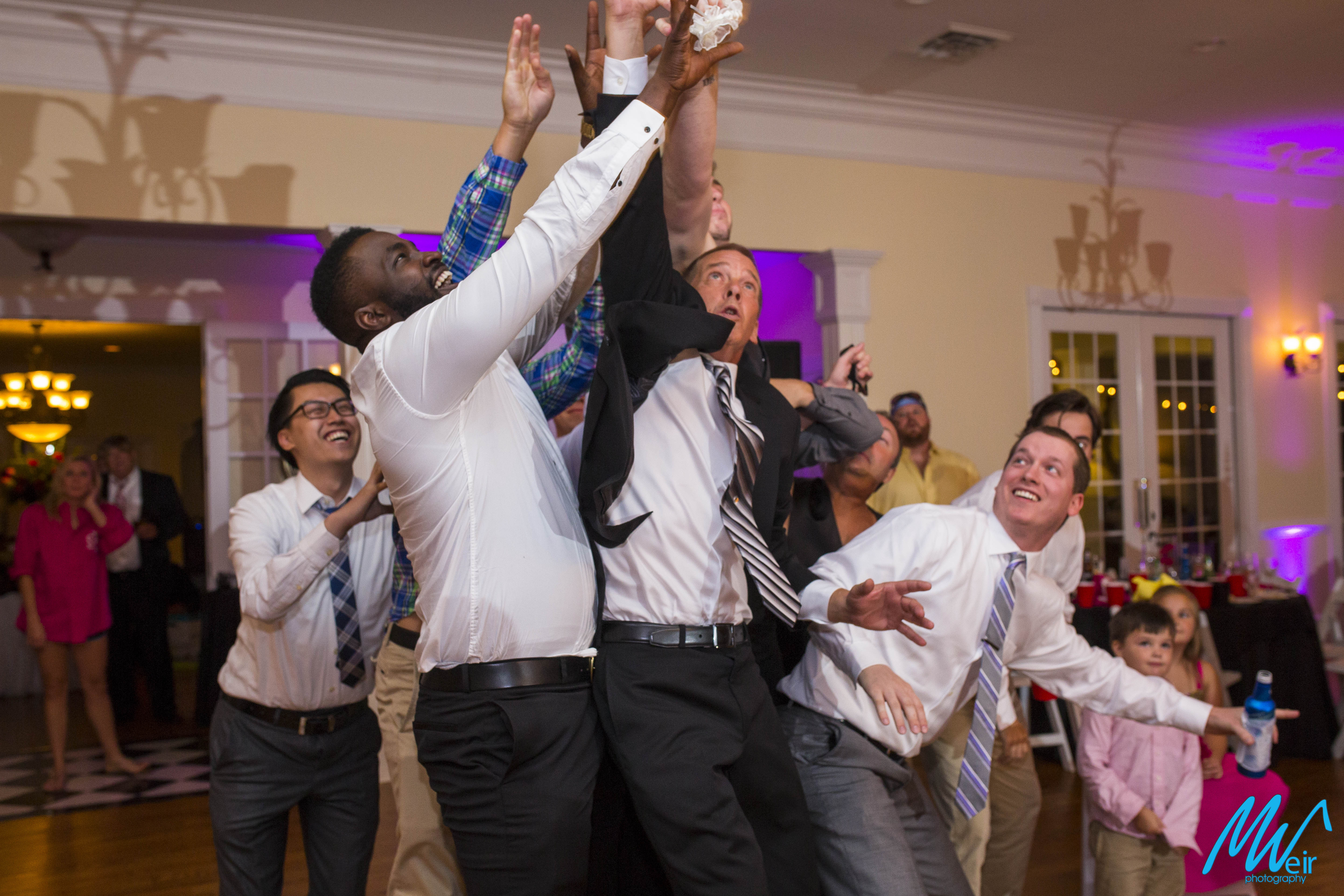 men catch garter during reception