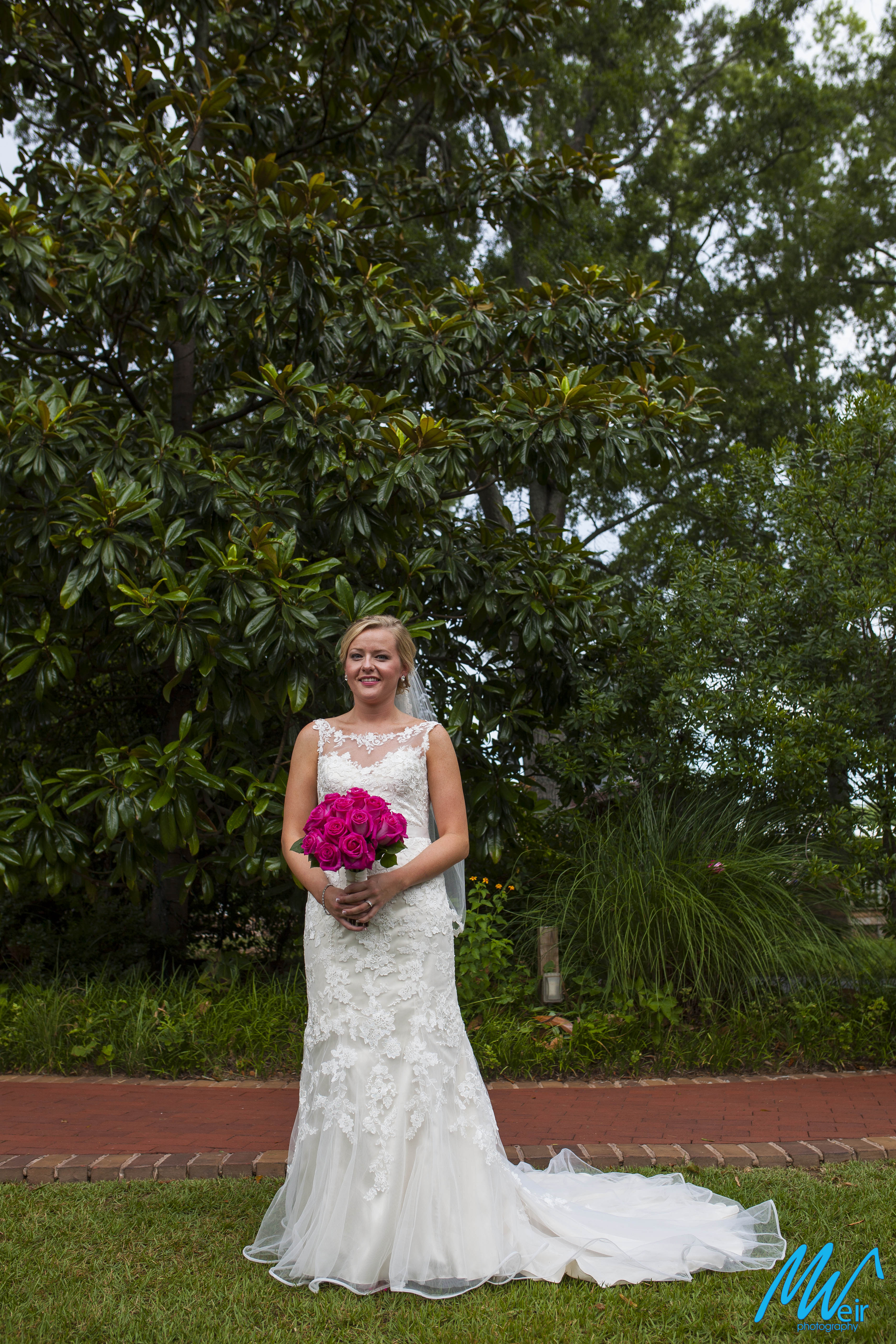 bride in lace gown standing in front of magnolia tree