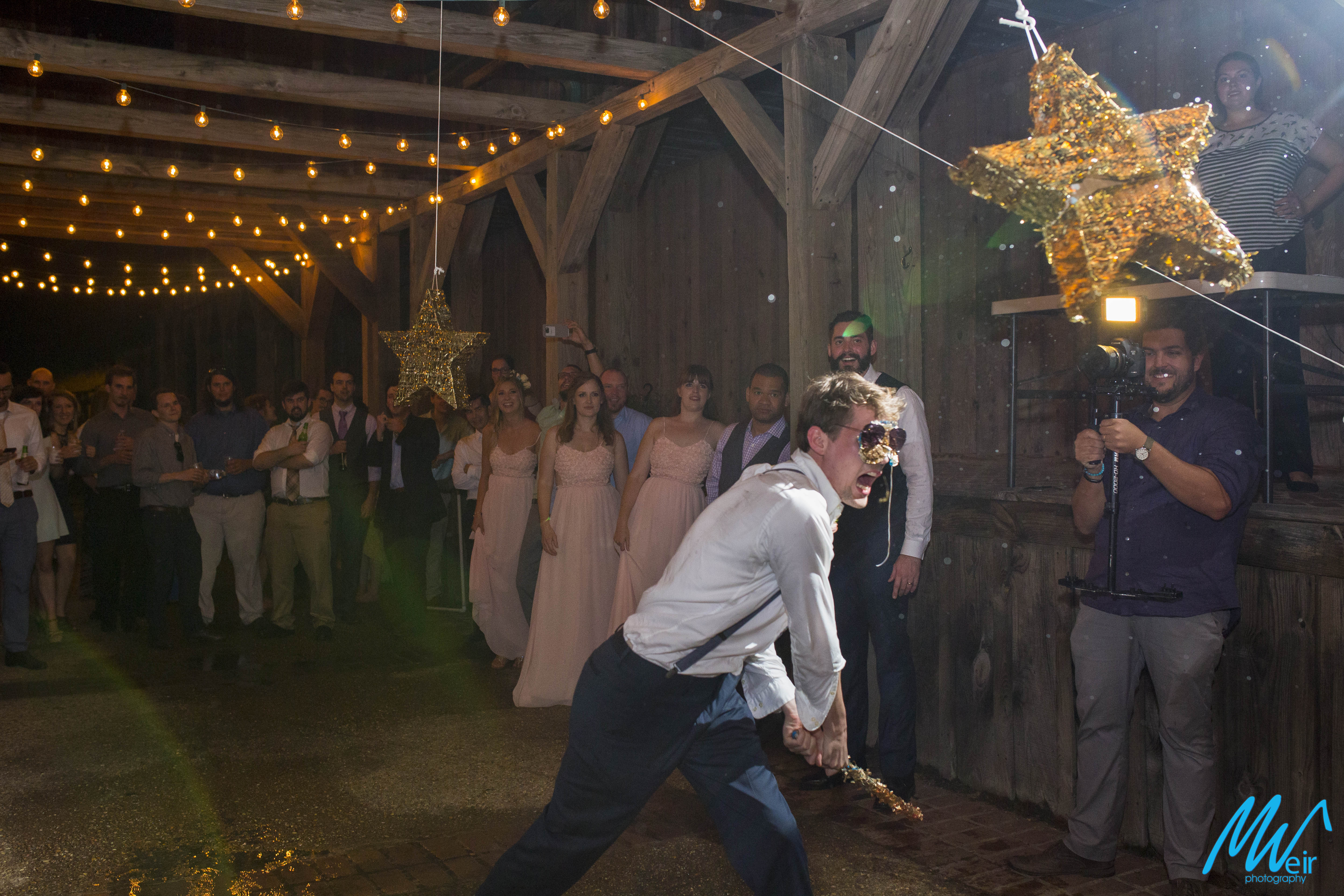 groomsmen hit a pinata at a outdoor wedding reception