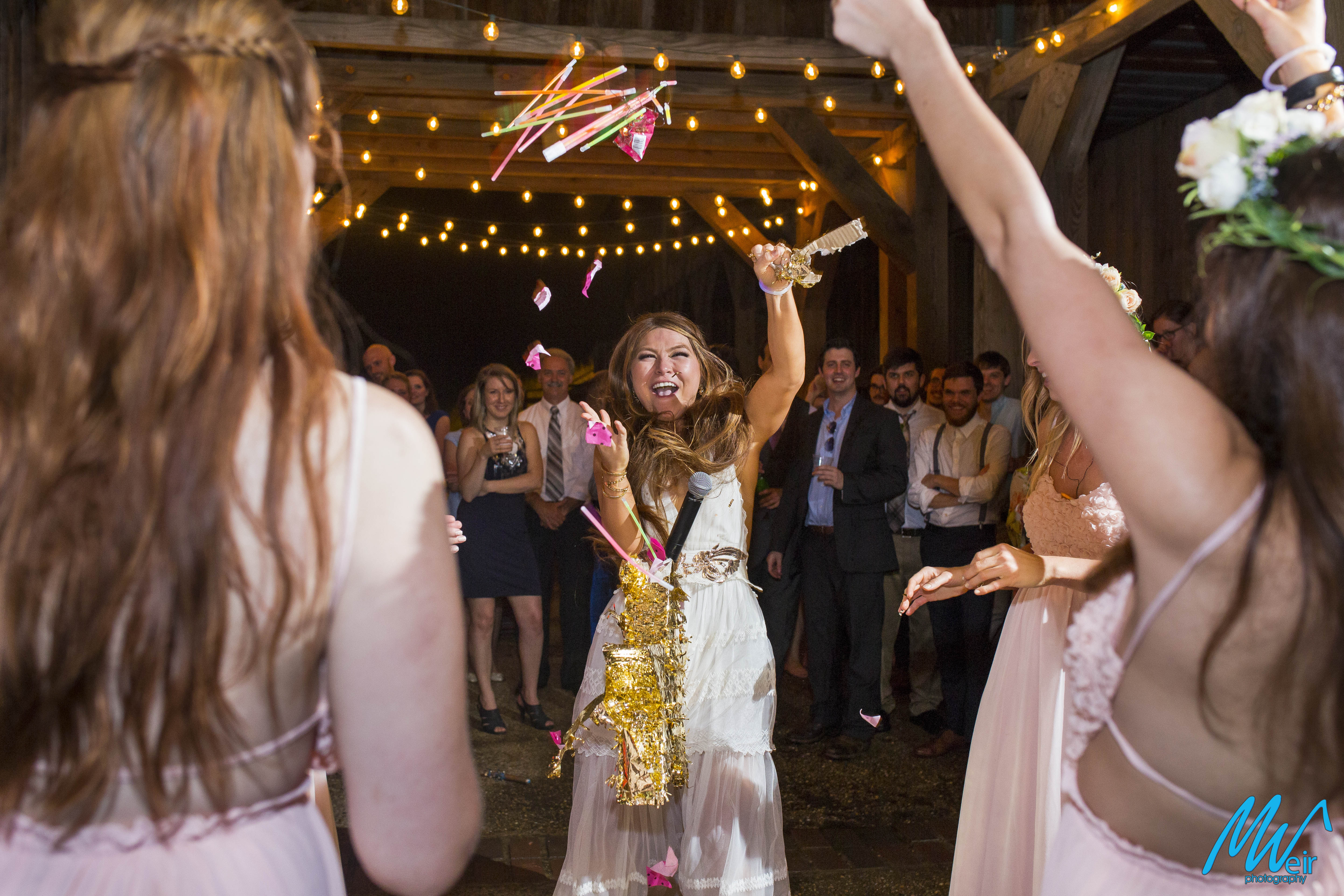 bride busts open a pinata at an outdoor reception 