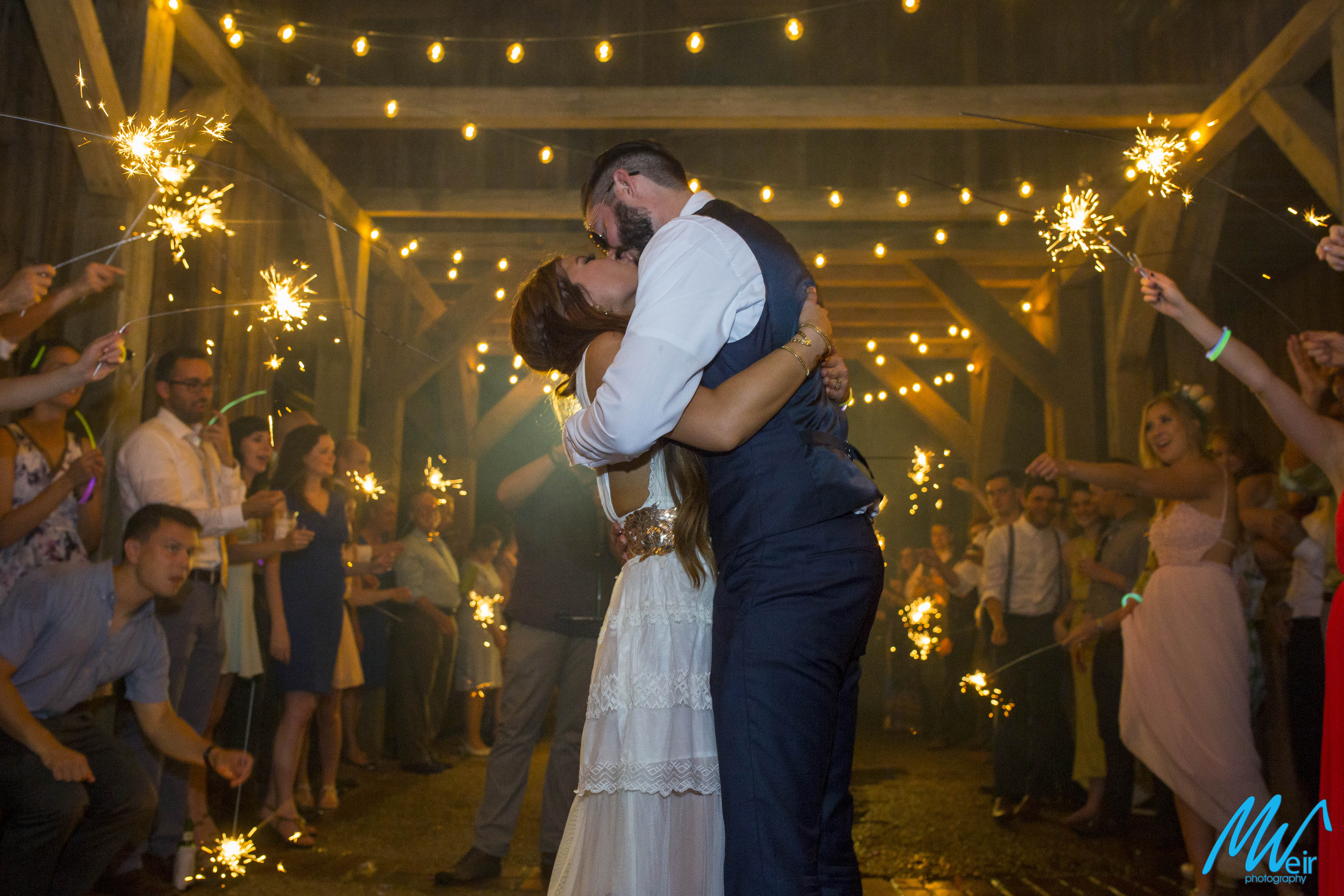 bride and groom kiss during their grand exit with sparklers